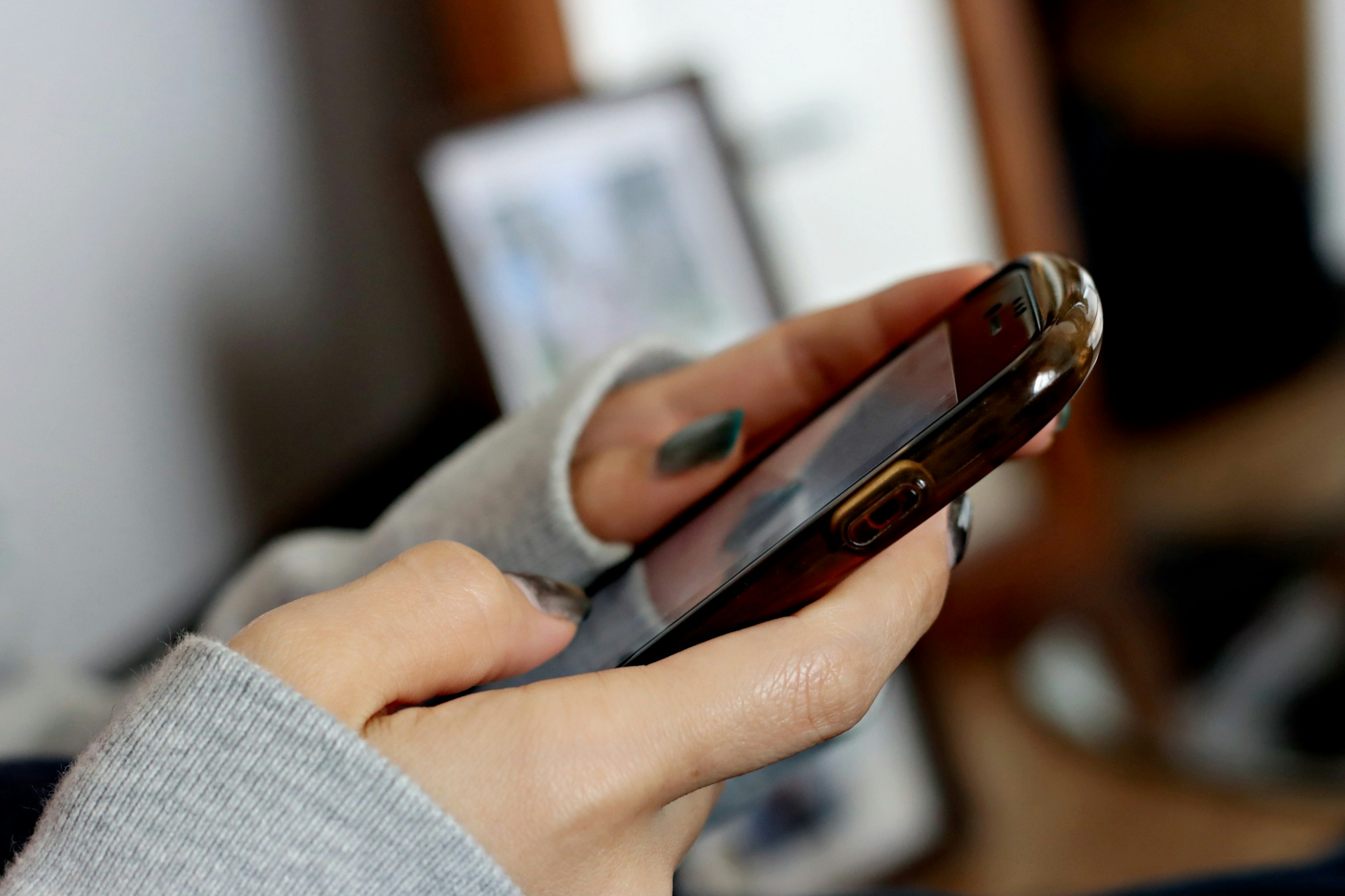 Close-up of a person holding a smartphone with visible sweater sleeve