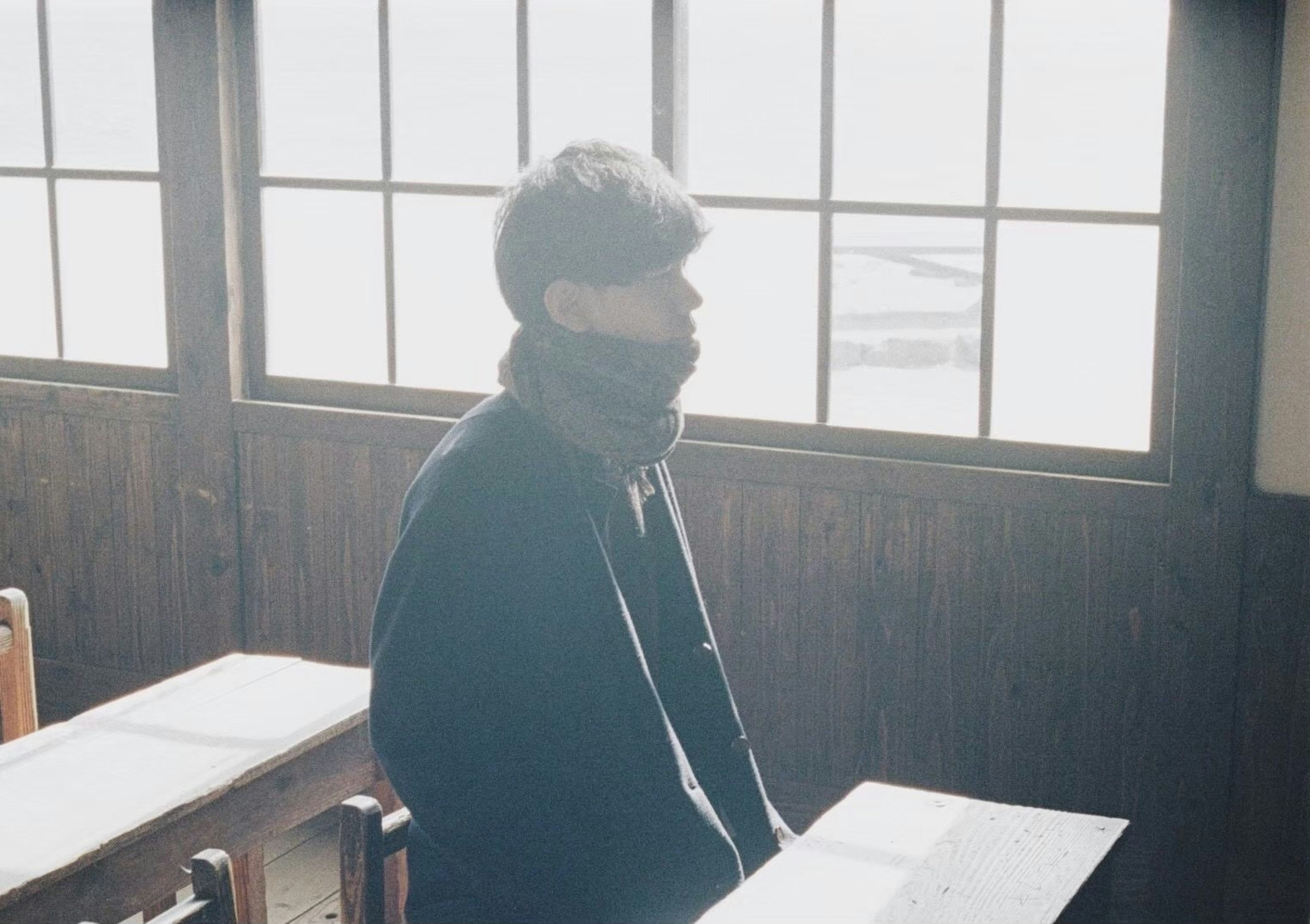 Side profile of a man sitting by the classroom window with warm light