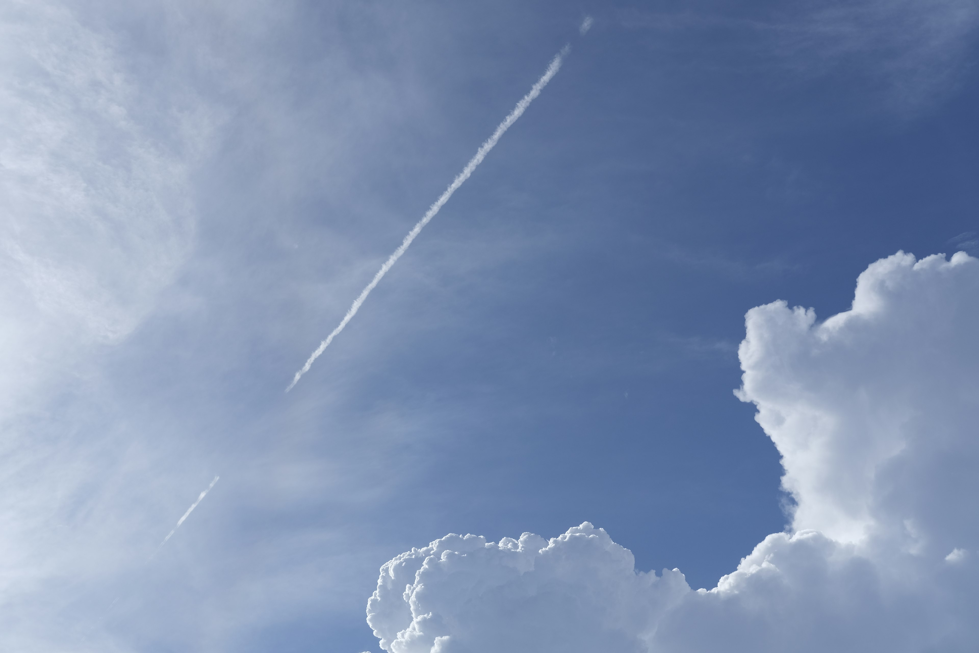 Himmel mit Wolken und einer Flugzeugspur