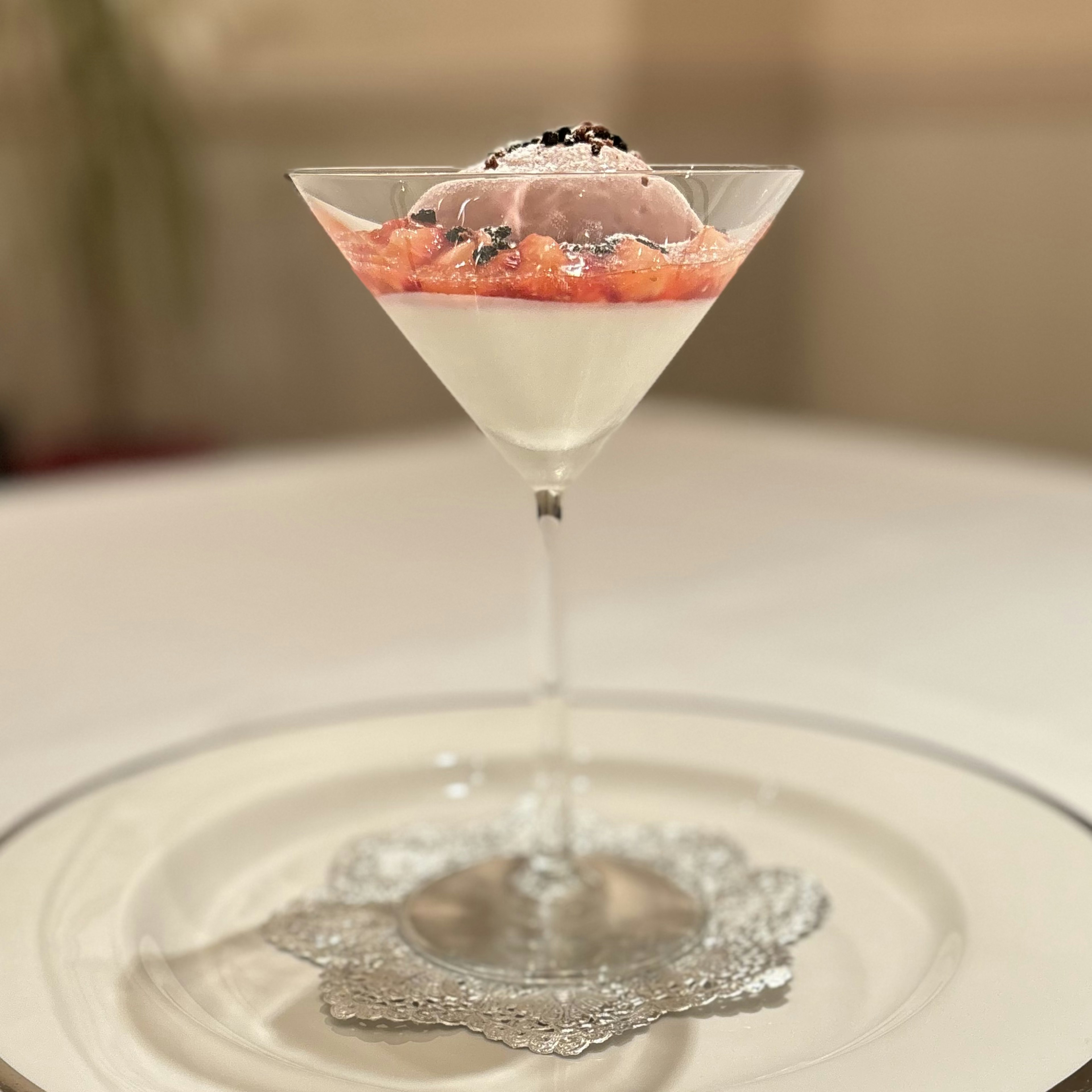 Elegant dessert in a cocktail glass featuring cream and fruit sauce