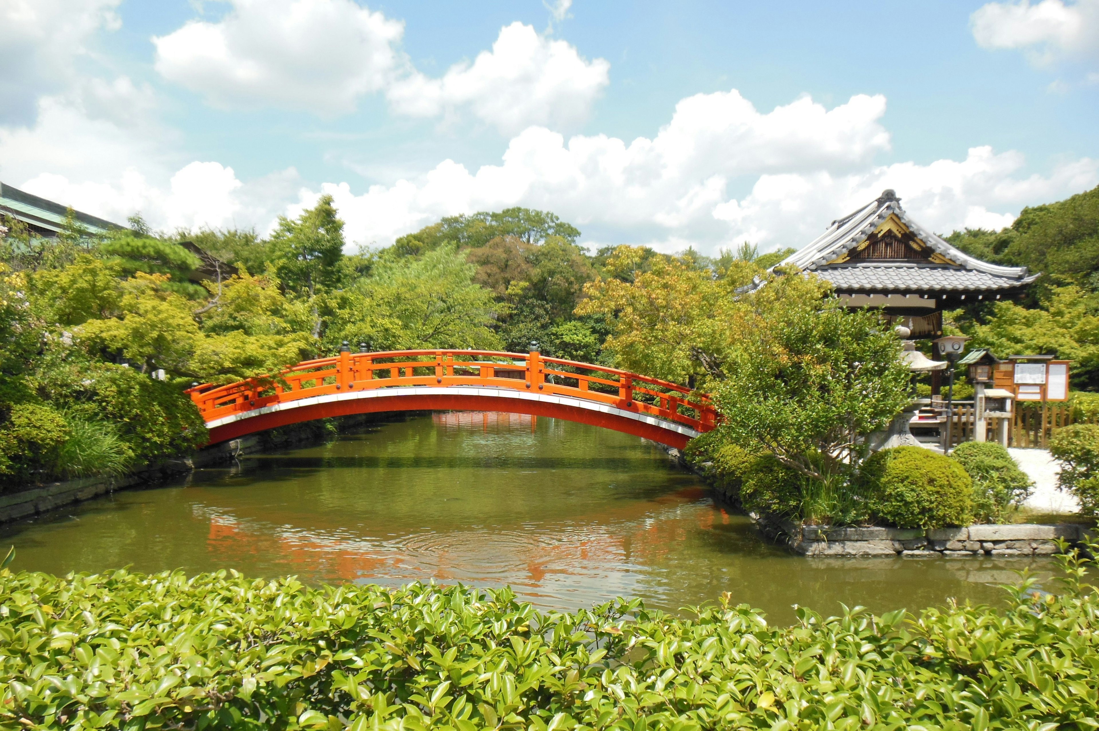 ทัศนียภาพของสะพานแดงข้ามสระน้ำในสวนญี่ปุ่น