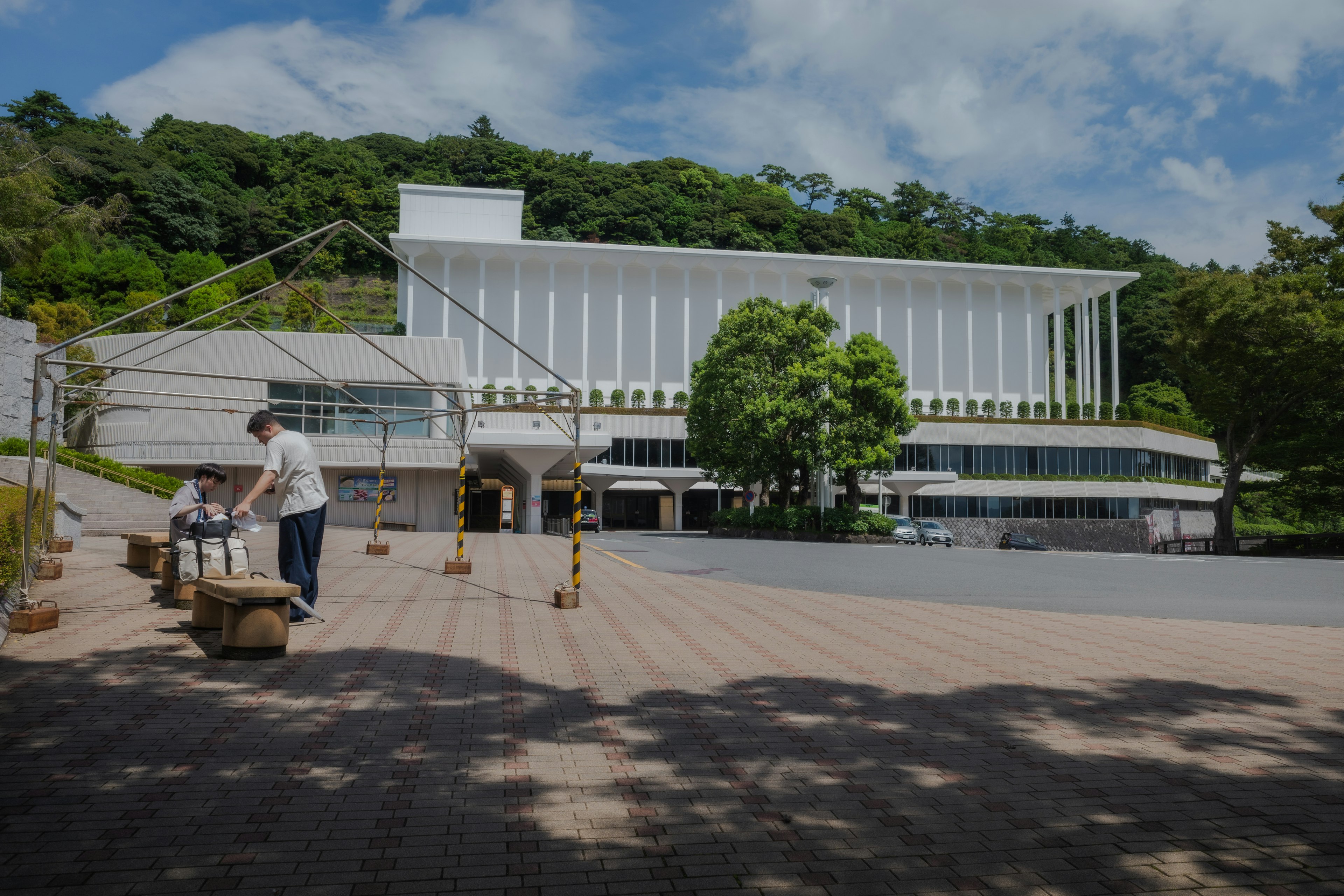 一座白色建築和綠色樹木以及在戶外工作的人的景象