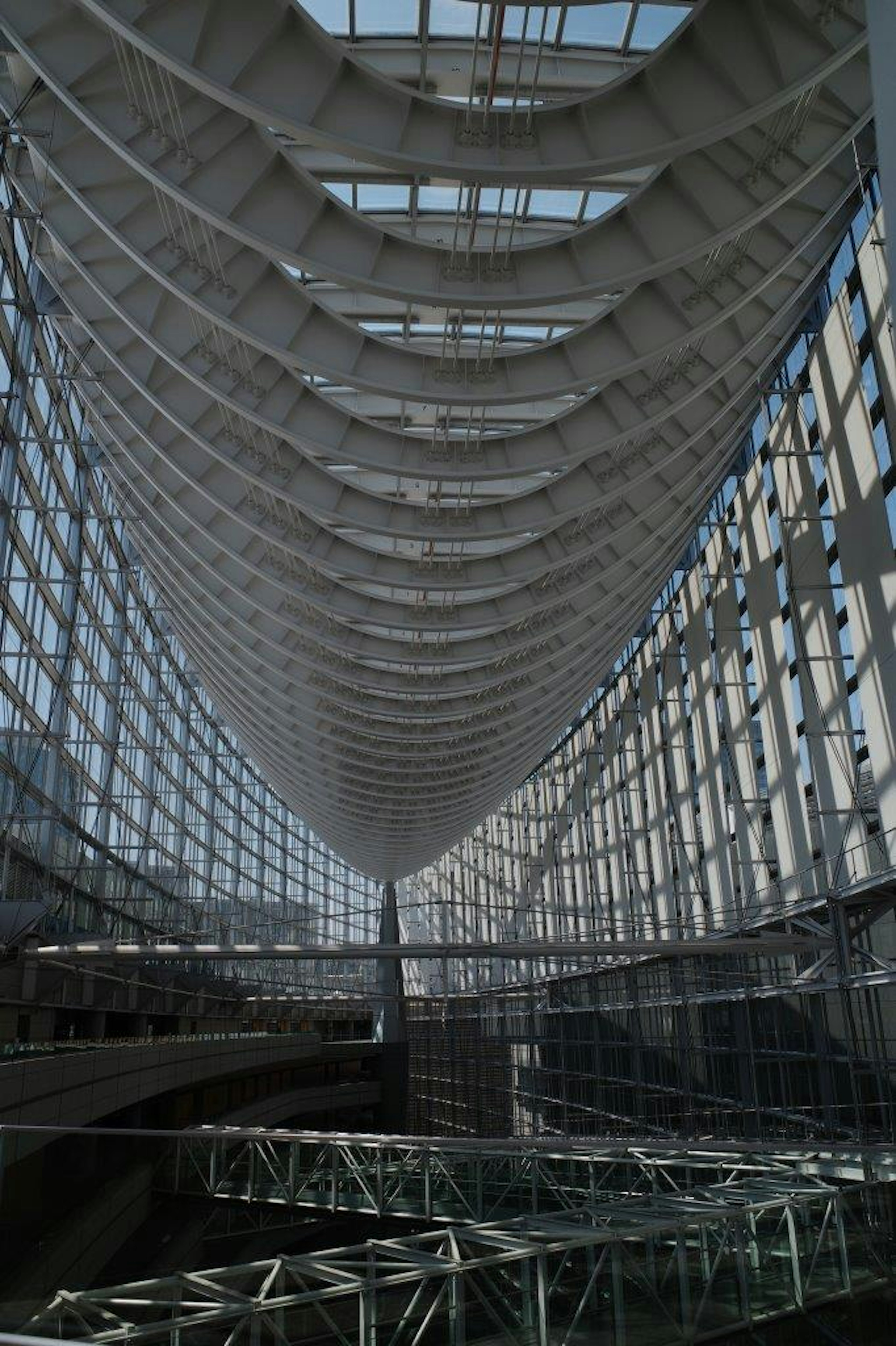 Vista interna di un grande edificio in vetro con struttura del tetto curvo