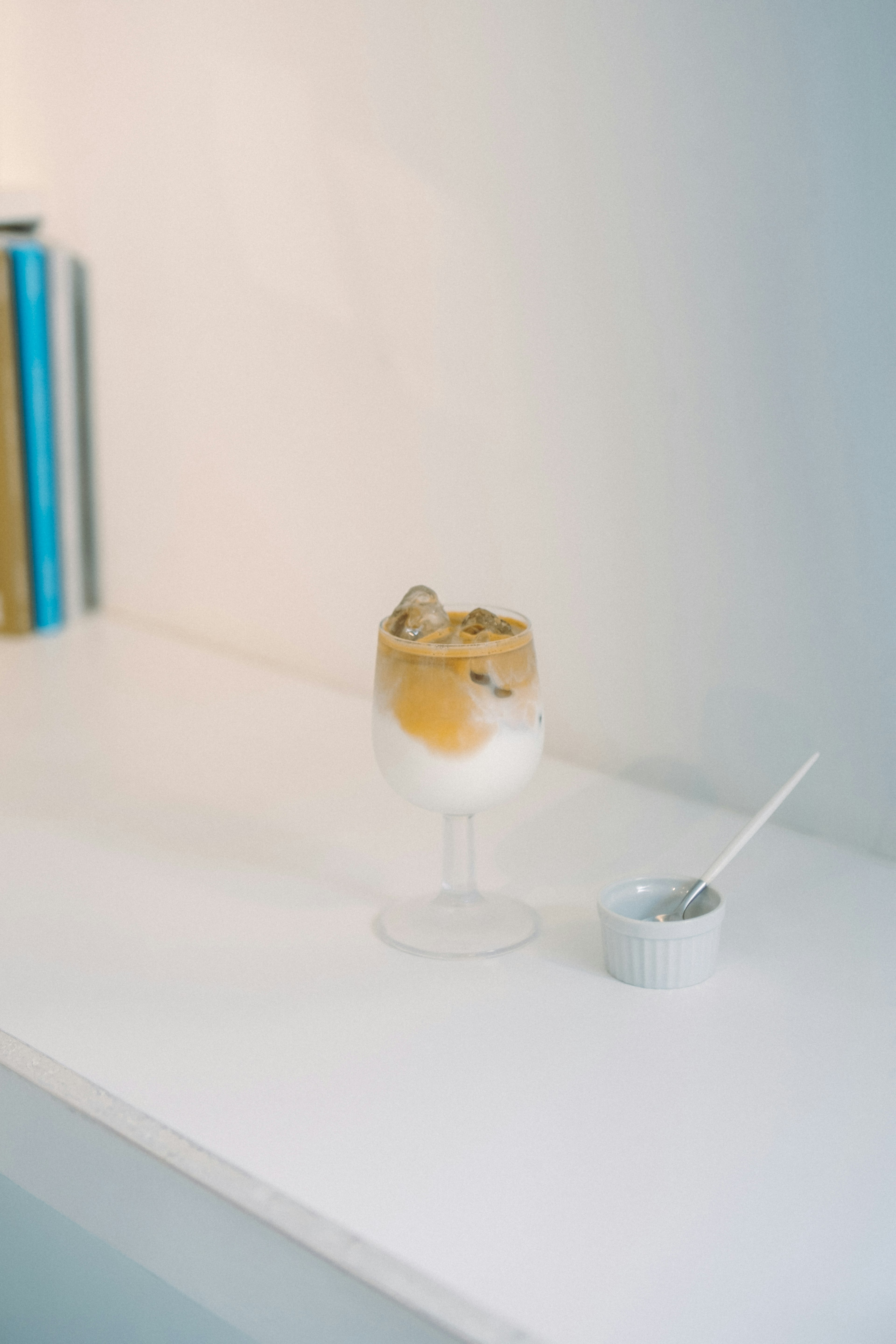 A dessert with ice cream and caramel sauce served in a clear glass on a white table