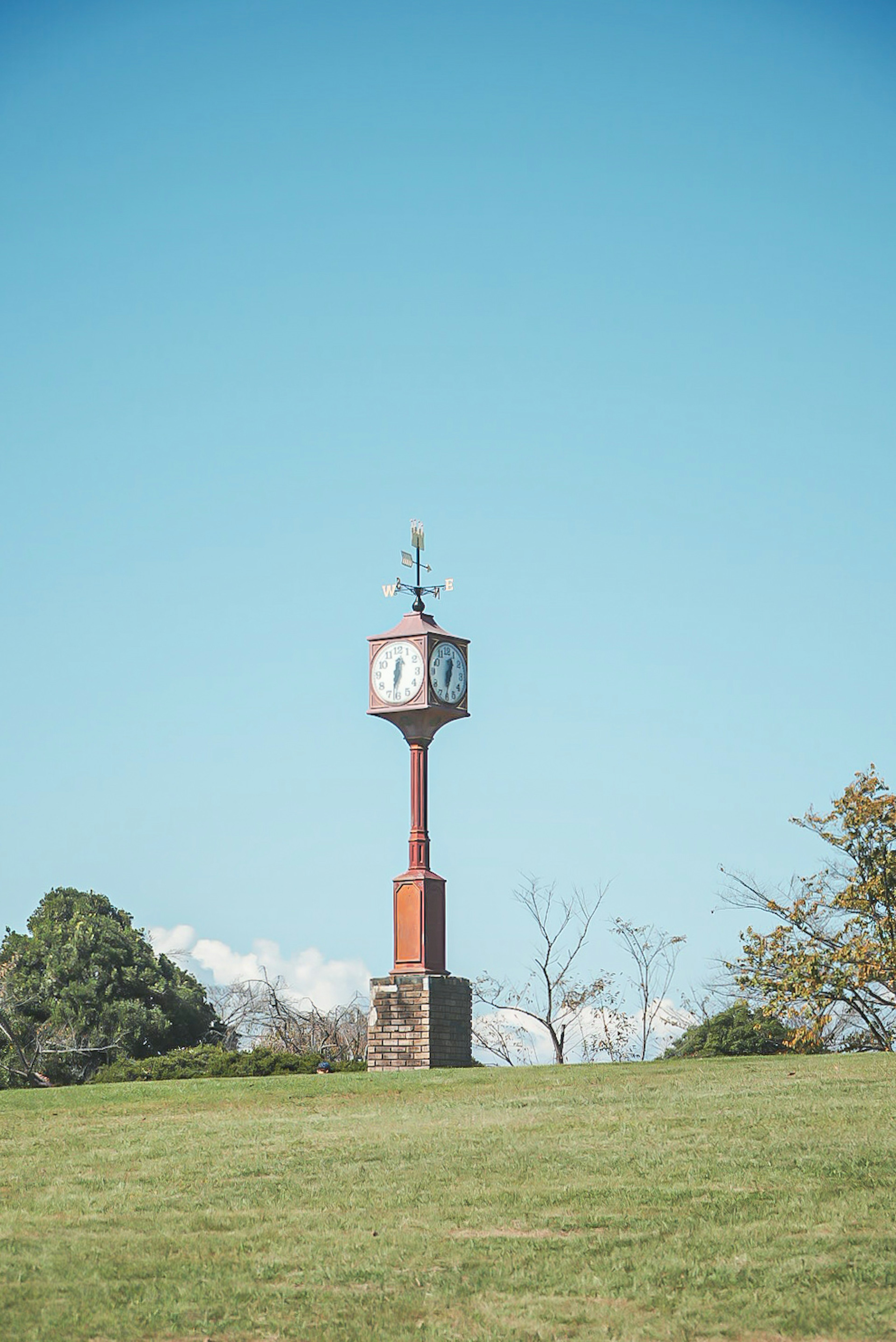 Old clock tower standing on green grass under blue sky