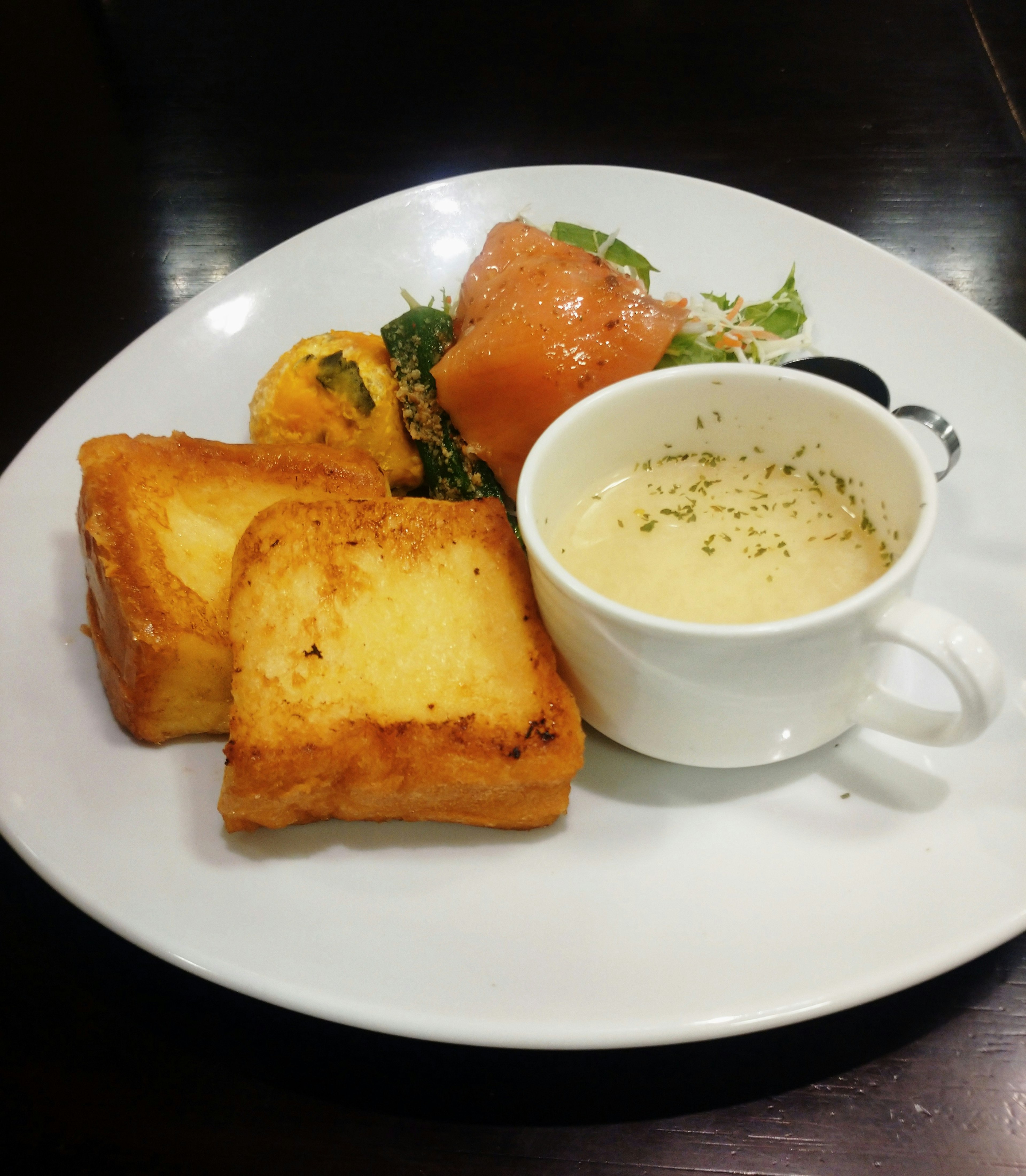 Un plato con pan tostado, salmón, ensalada y sopa de crema