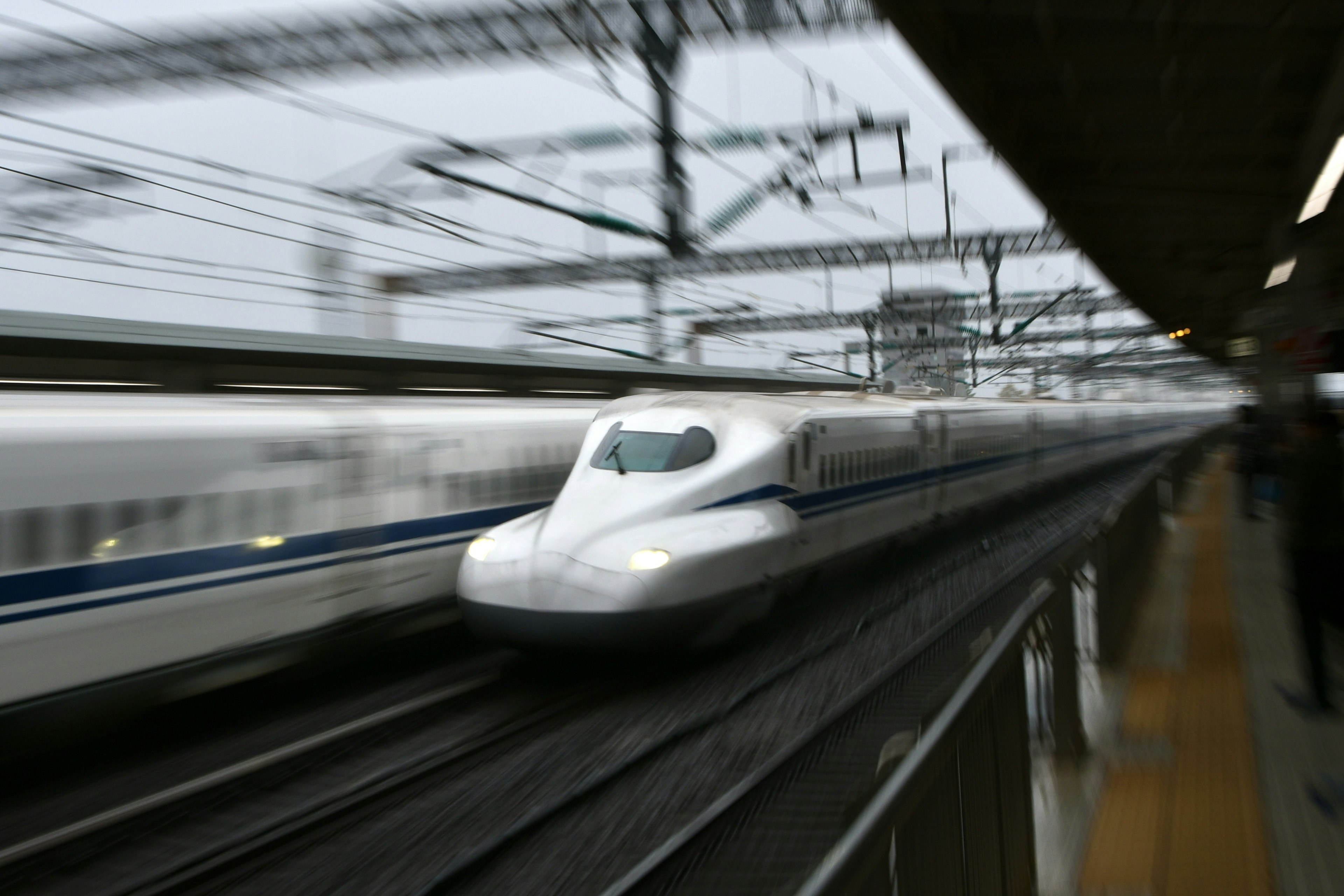 新幹線が高速で走行している様子 鉄道の線路と架線が見える