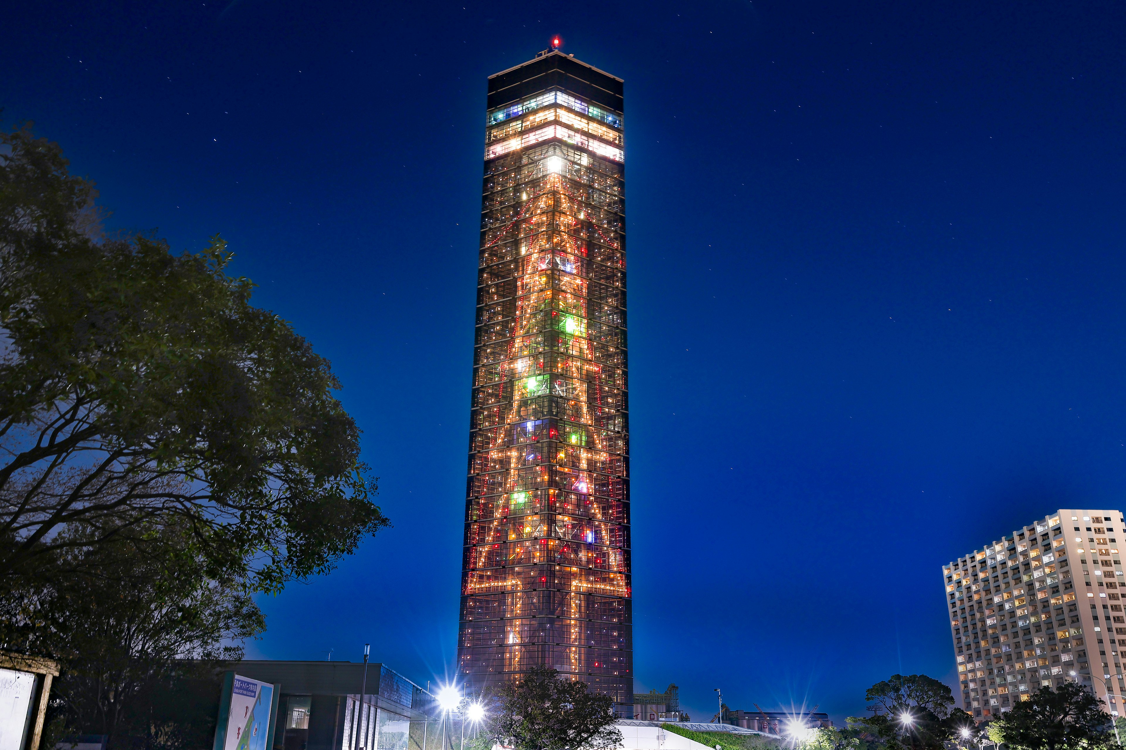 Colorful lights decorate a tall building against the night sky