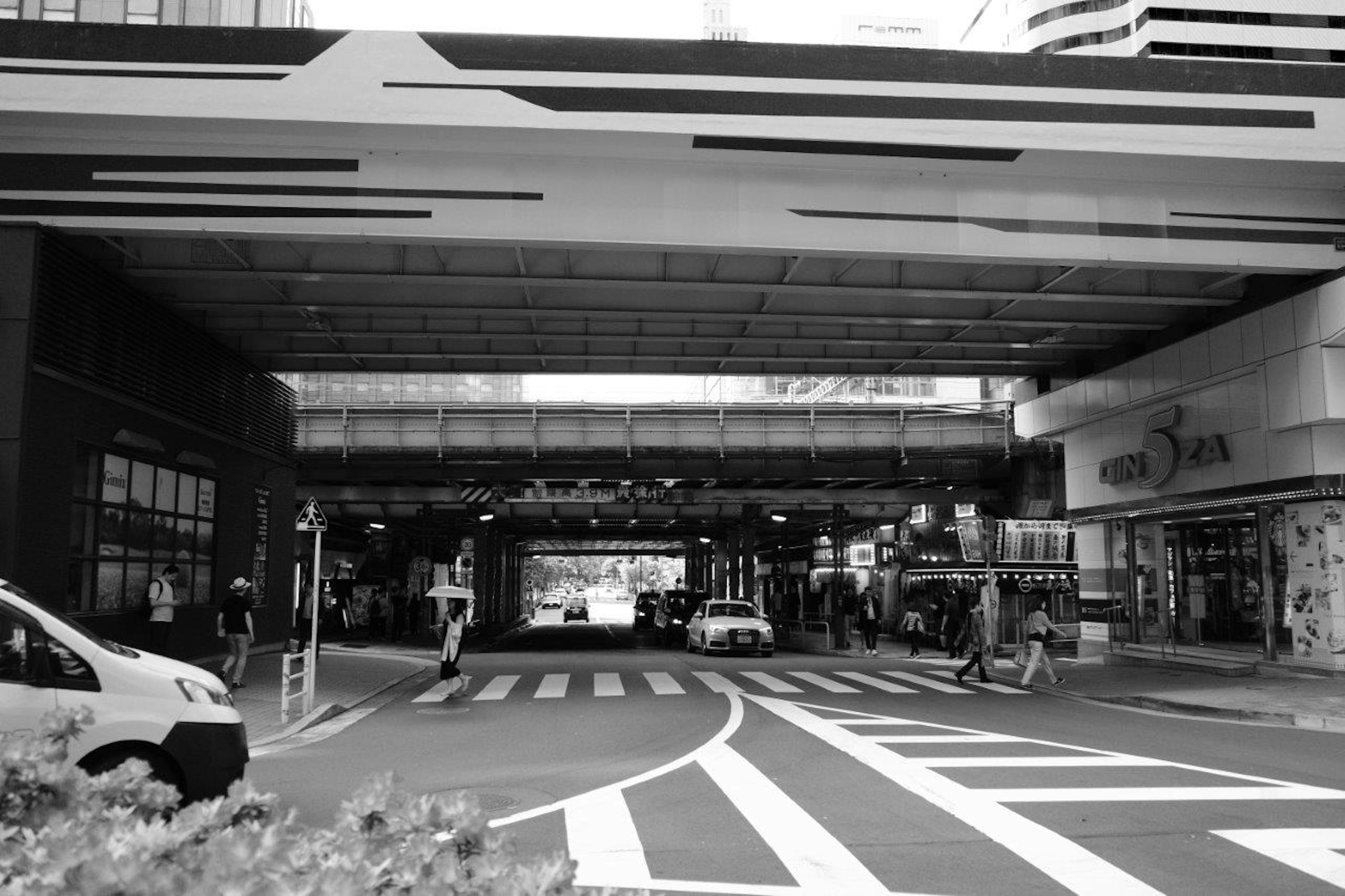 Image en noir et blanc d'une intersection urbaine avec des passages piétons et des véhicules