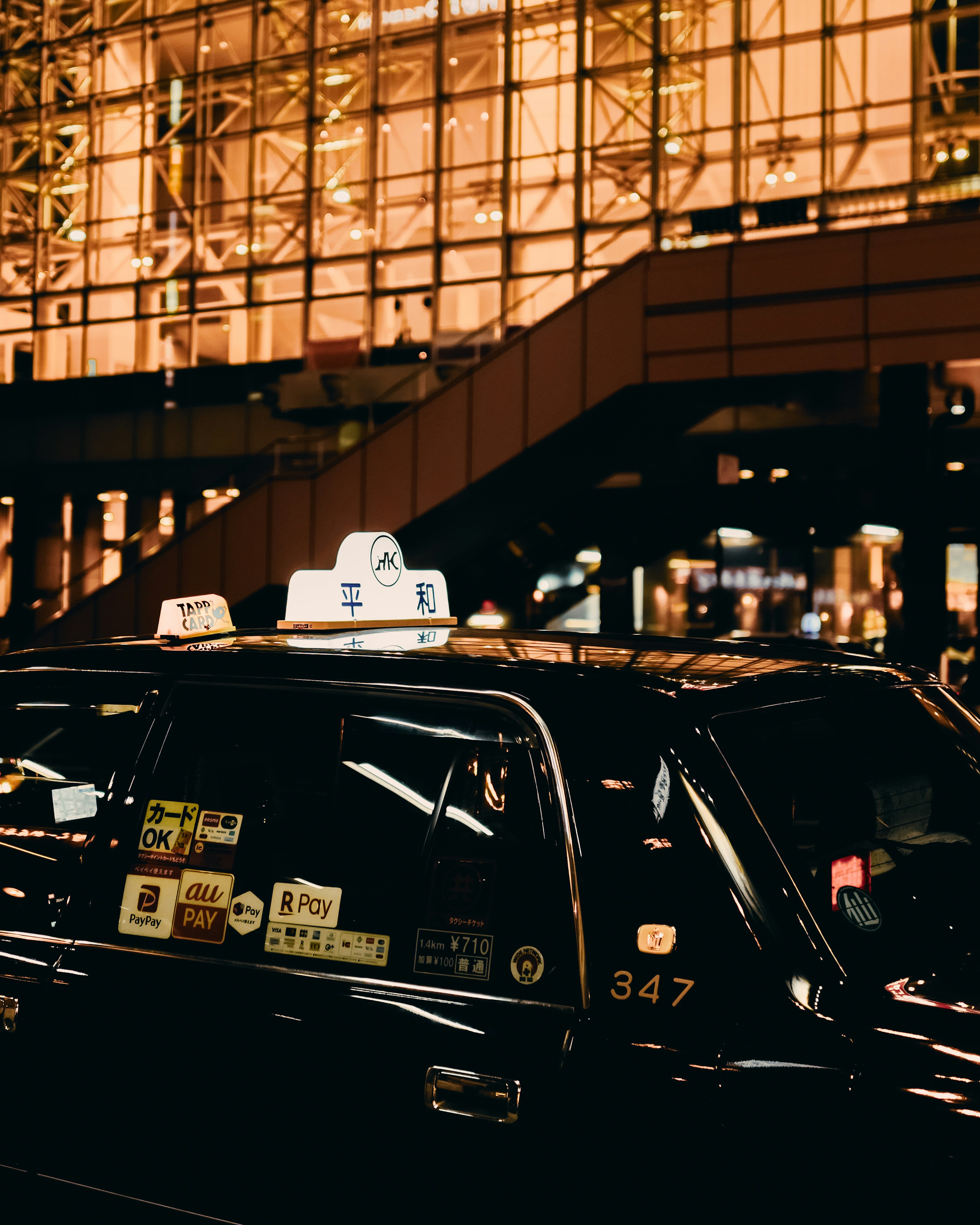 Taxi de noche con un edificio iluminado al fondo