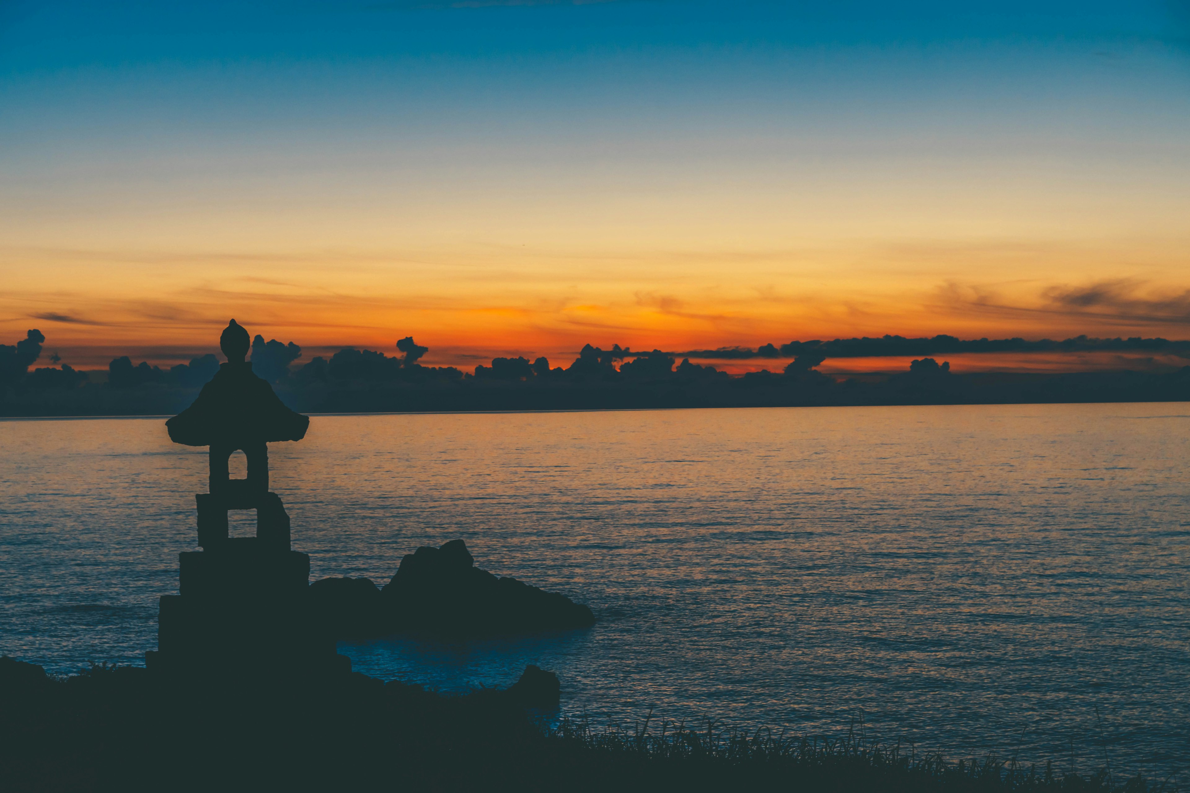 Silueta de una linterna contra un atardecer sobre el mar