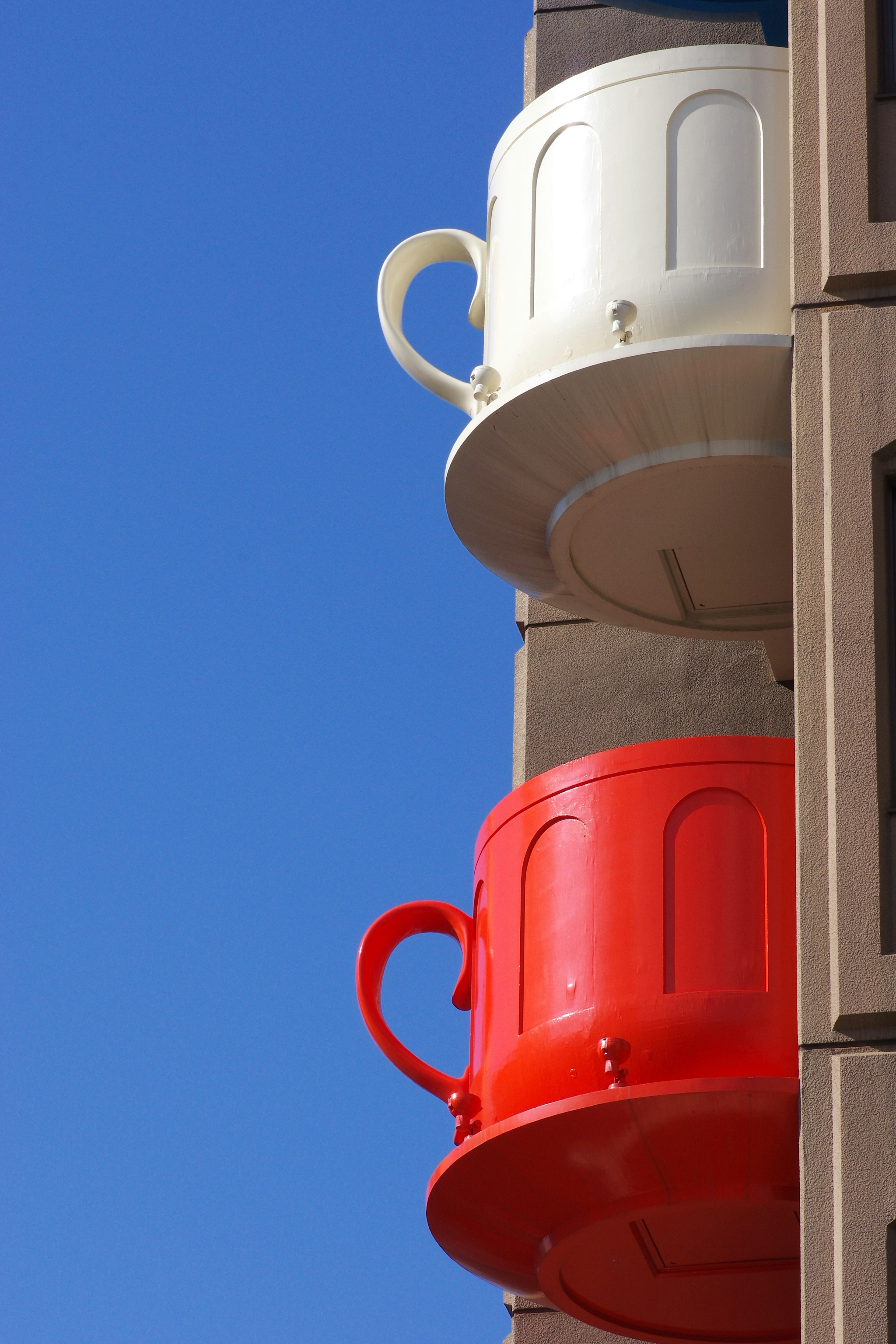 Stack of large red and white cups against a blue sky