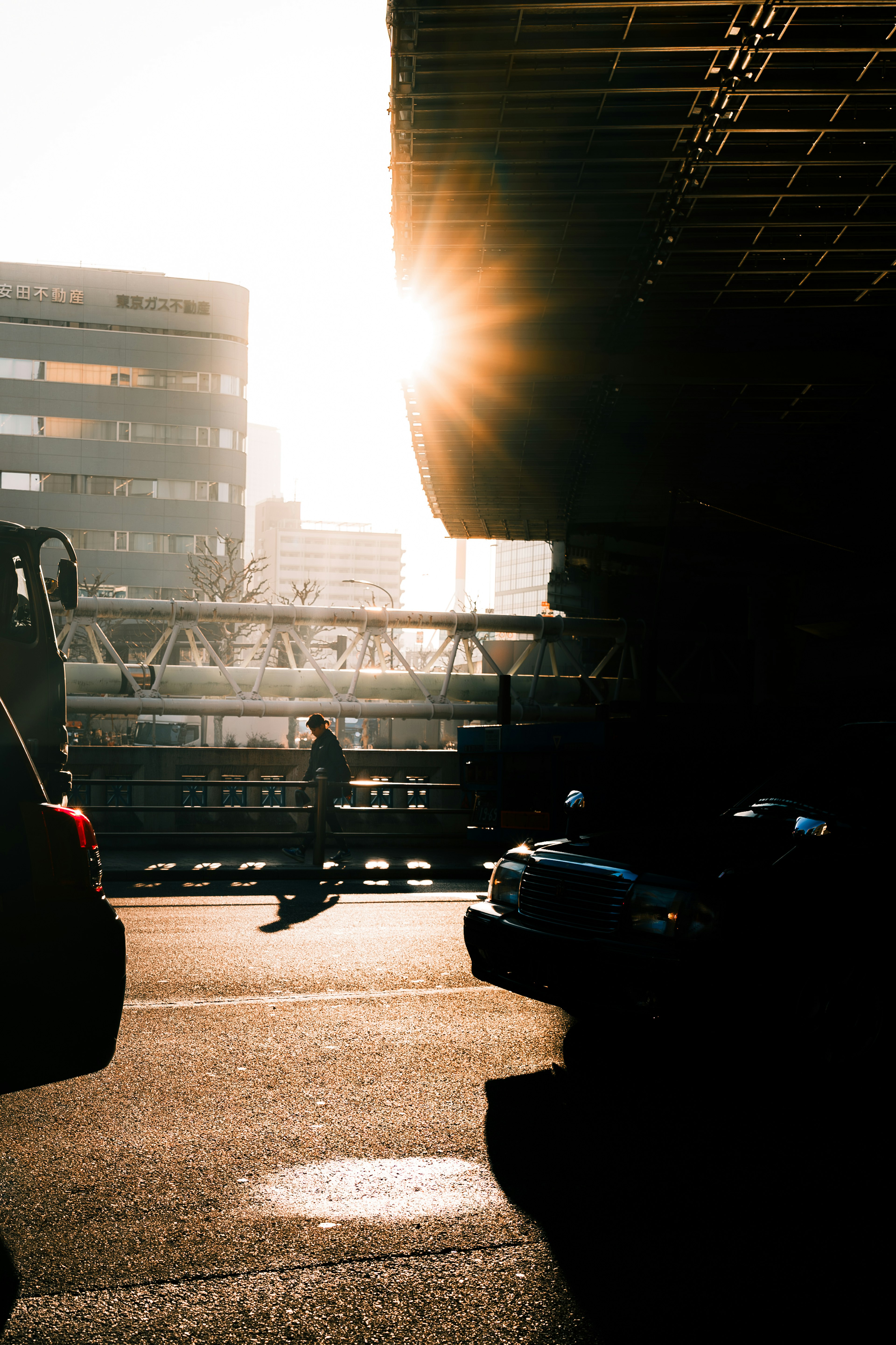 Urban scene with sunlight shining through buildings a person riding a bicycle and cars passing by