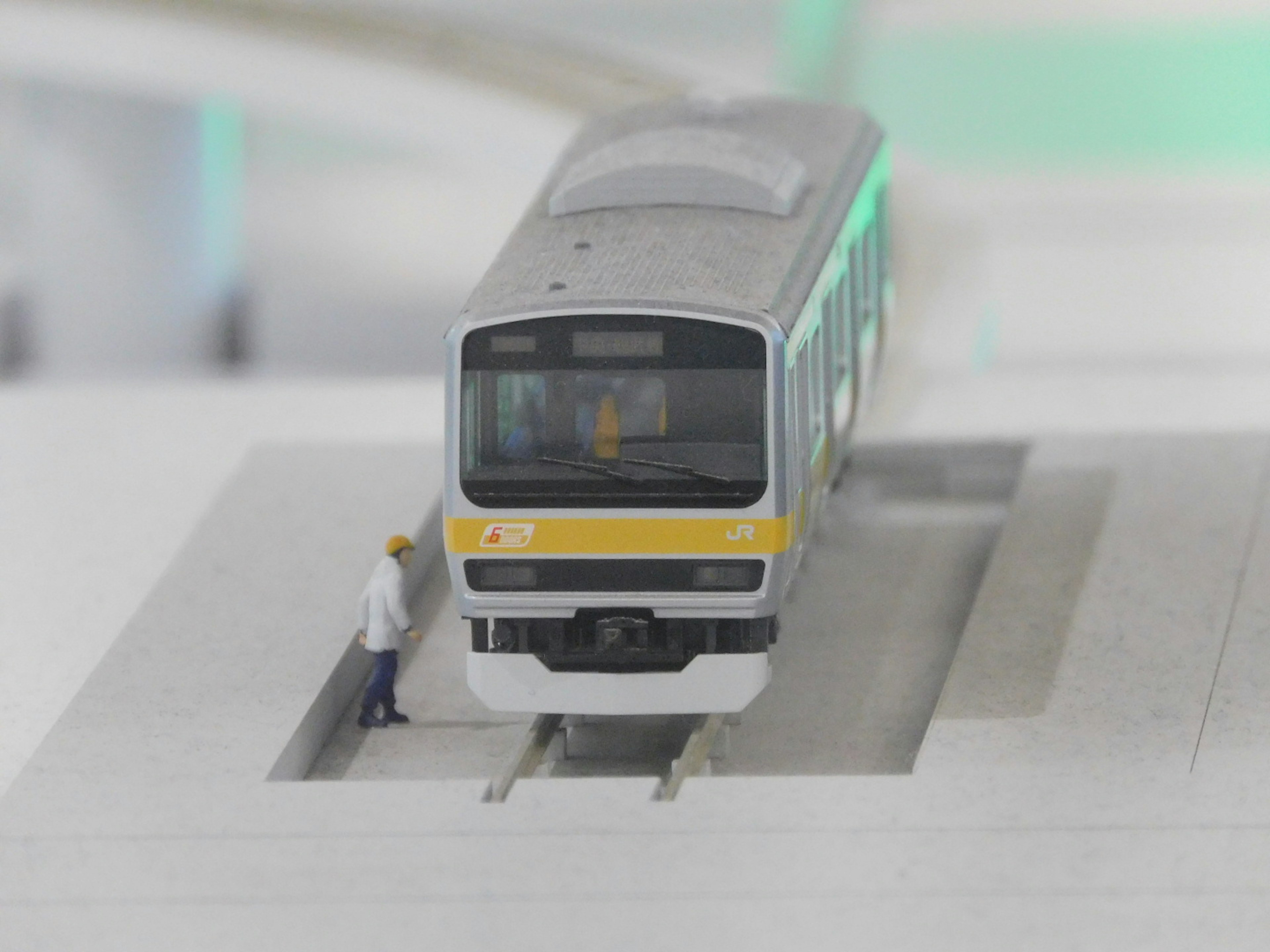 Un train miniature sur des rails avec une figurine à côté