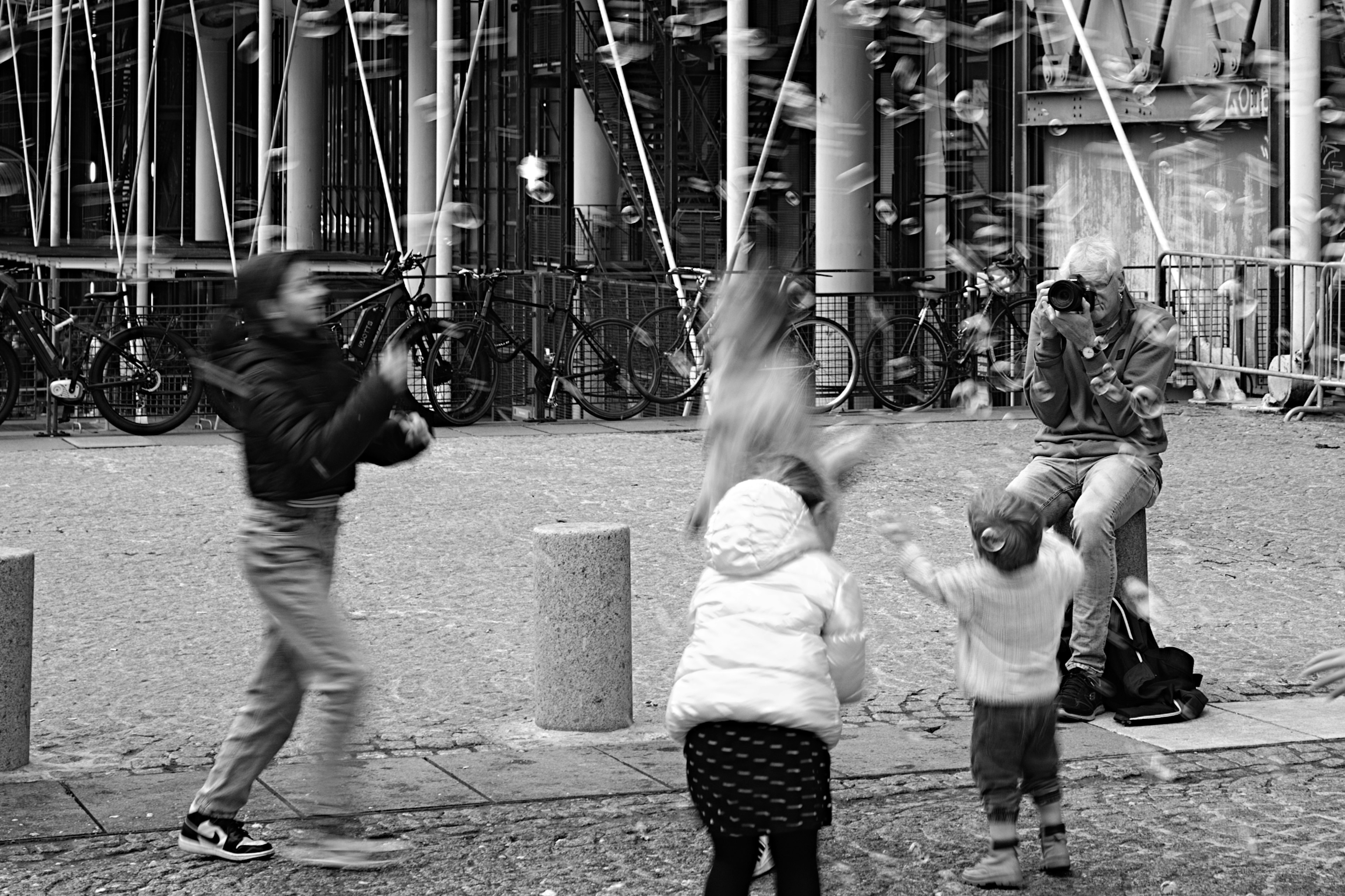 Children and adults playing in a city square captured in black and white