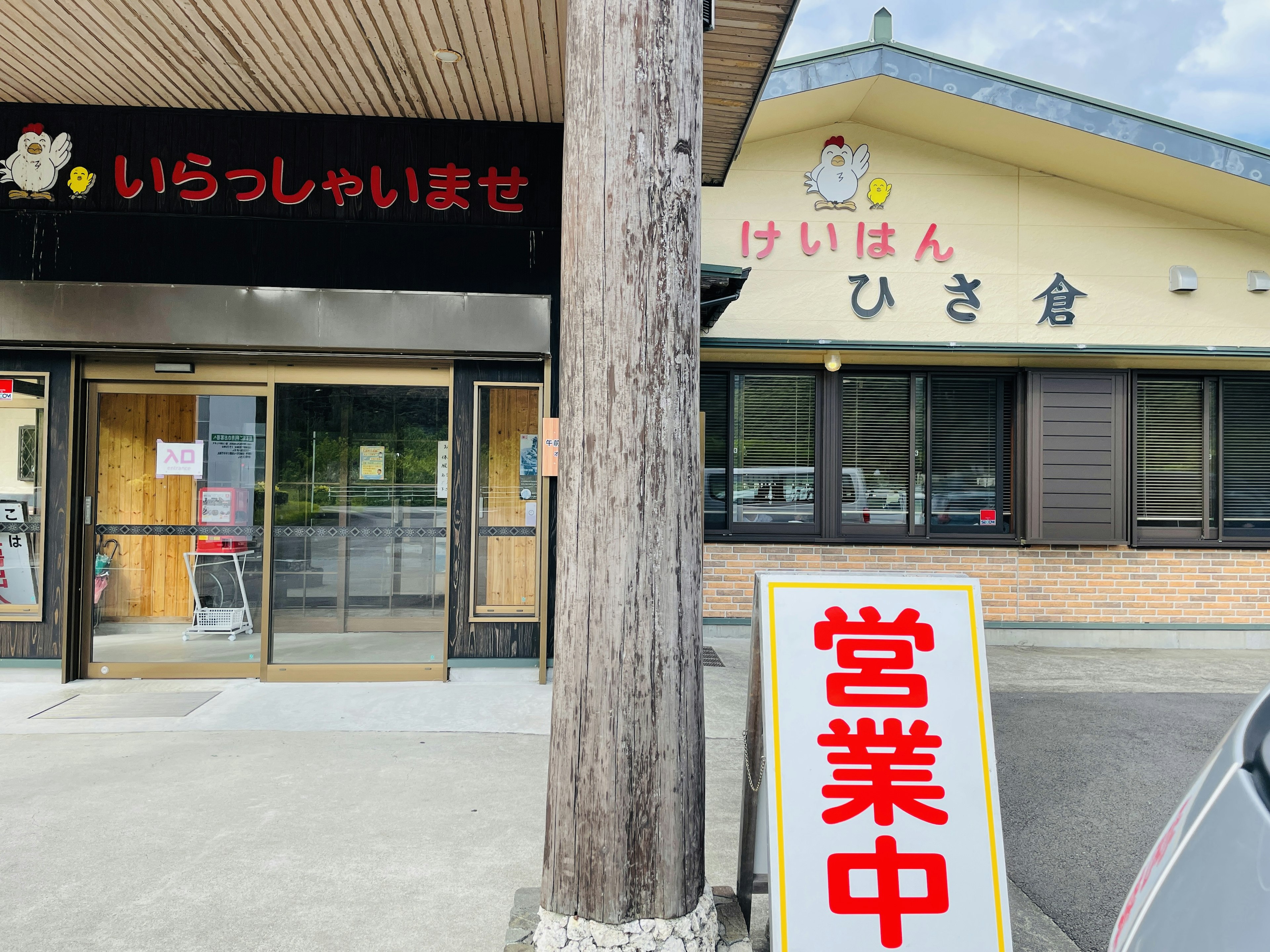 ภาพภายนอกของร้านอาหารที่มีป้ายภาษาญี่ปุ่นและป้ายเปิด