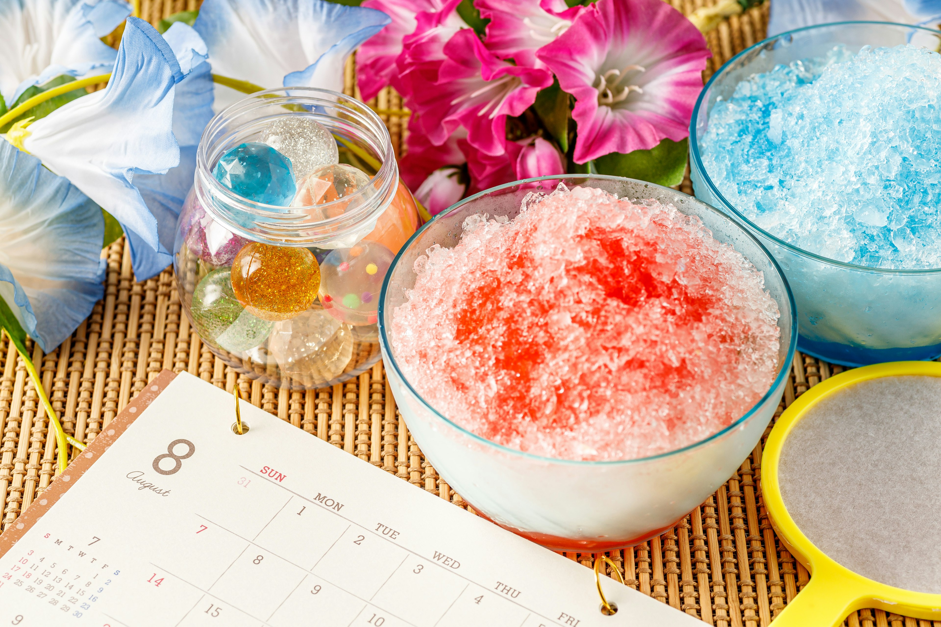 Colorful shaved ice desserts with flowers and a calendar in a summer setting