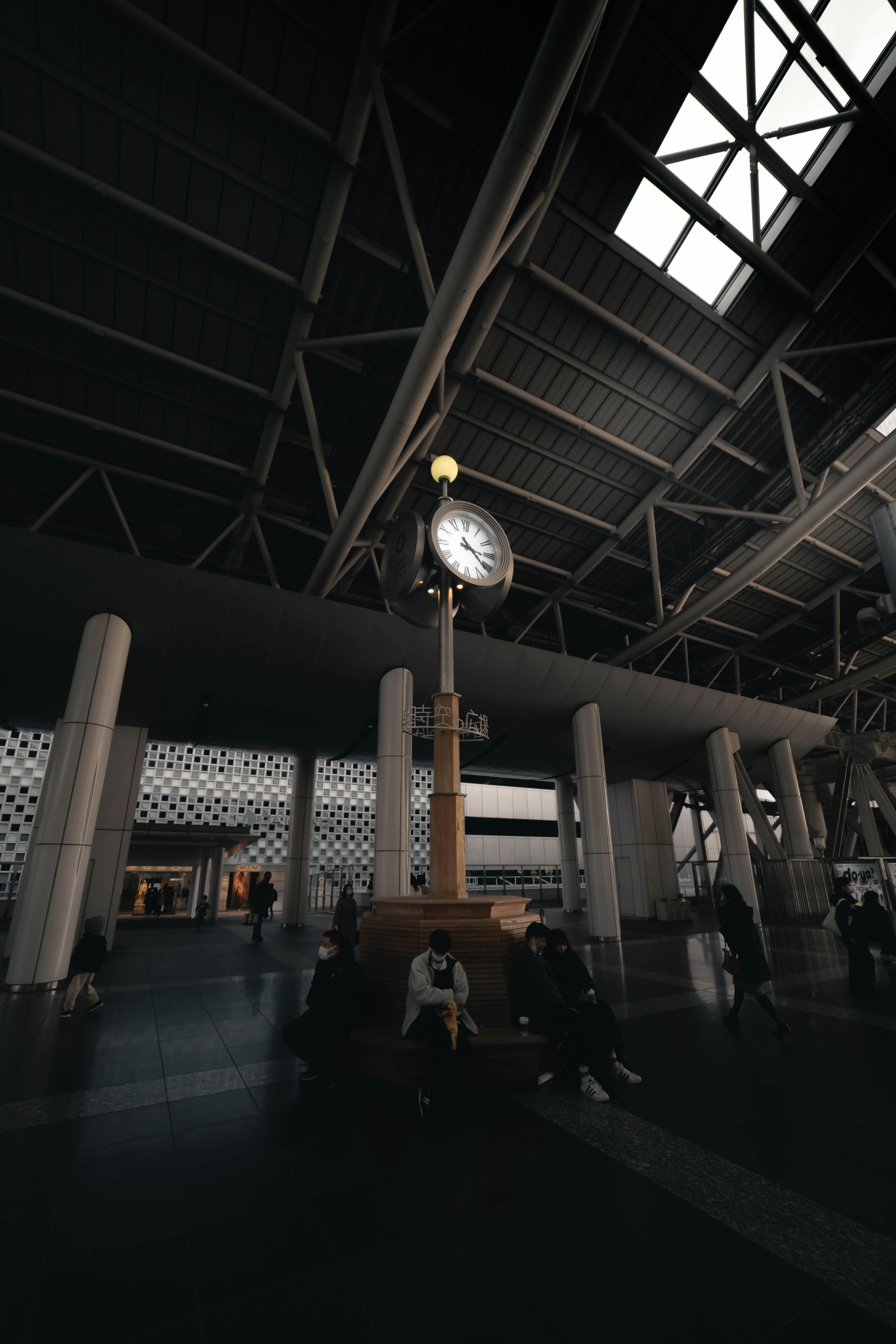 Large clock in a station with nearby people