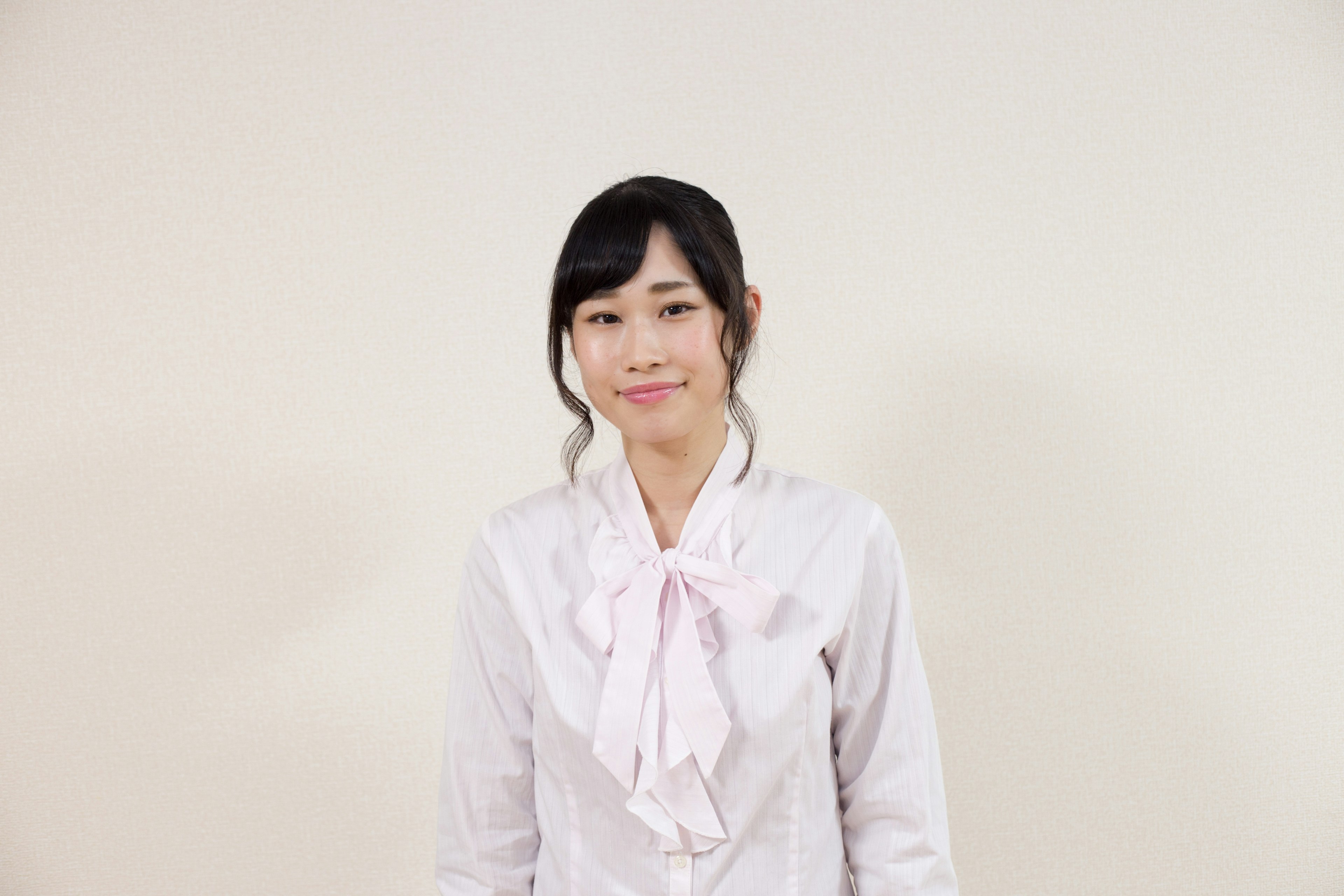 A woman smiling in a white blouse with a bow tie