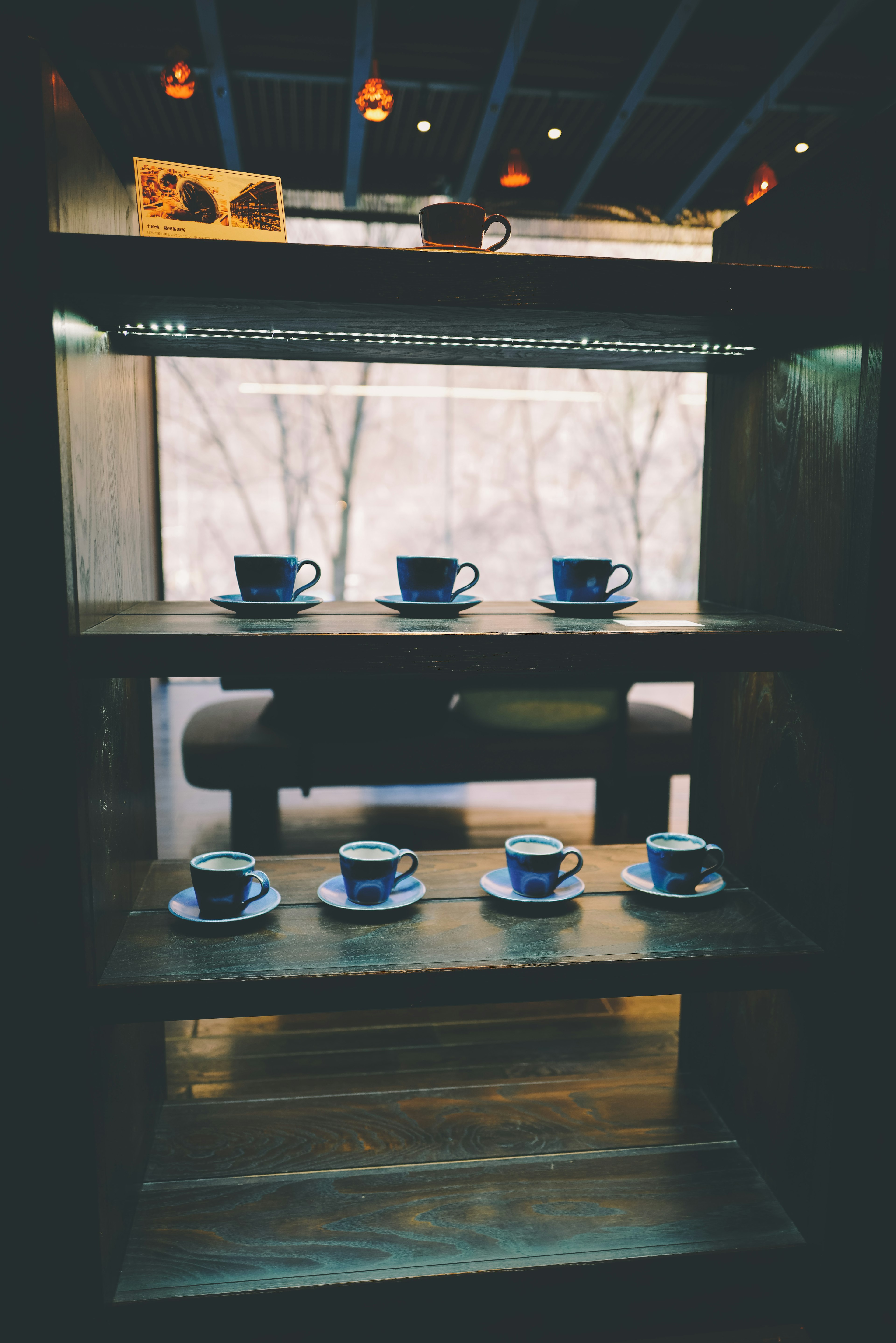 Interior de una cafetería con una estantería de madera que muestra tazas y platos azules