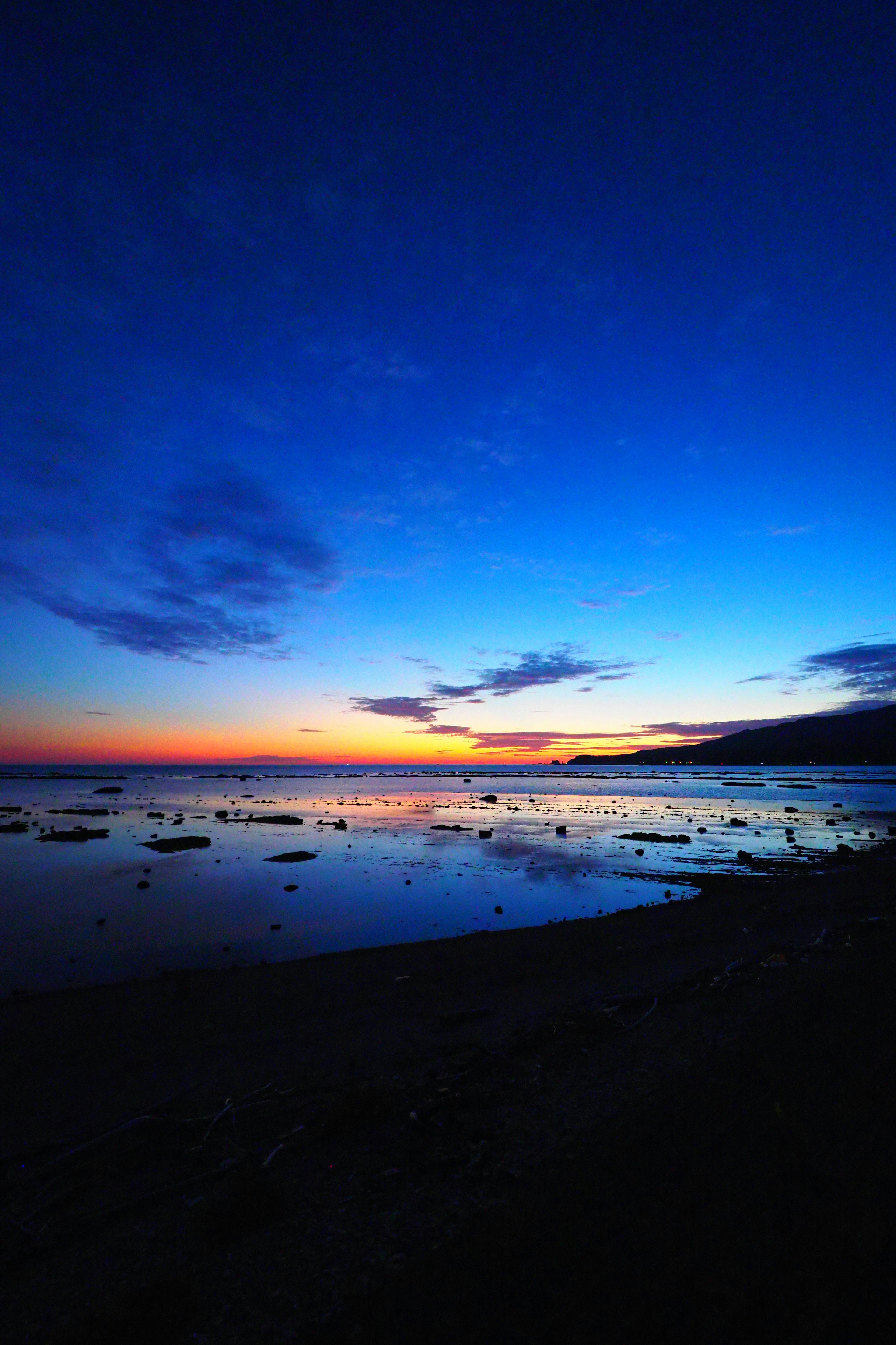 Un tramonto spettacolare con cielo blu e tonalità arancioni su un mare calmo