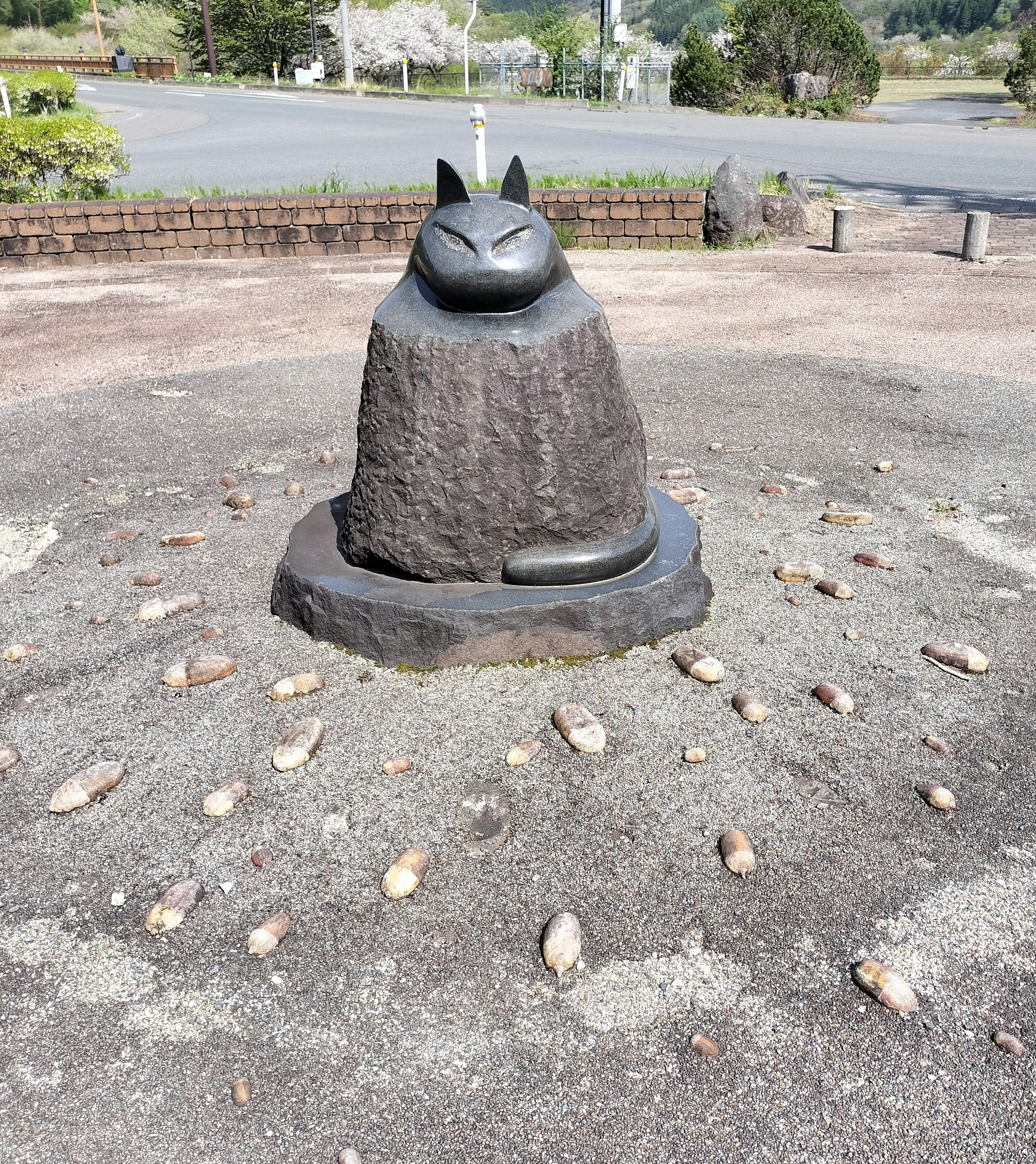 黒い猫の彫刻が石の台座の上にある風景