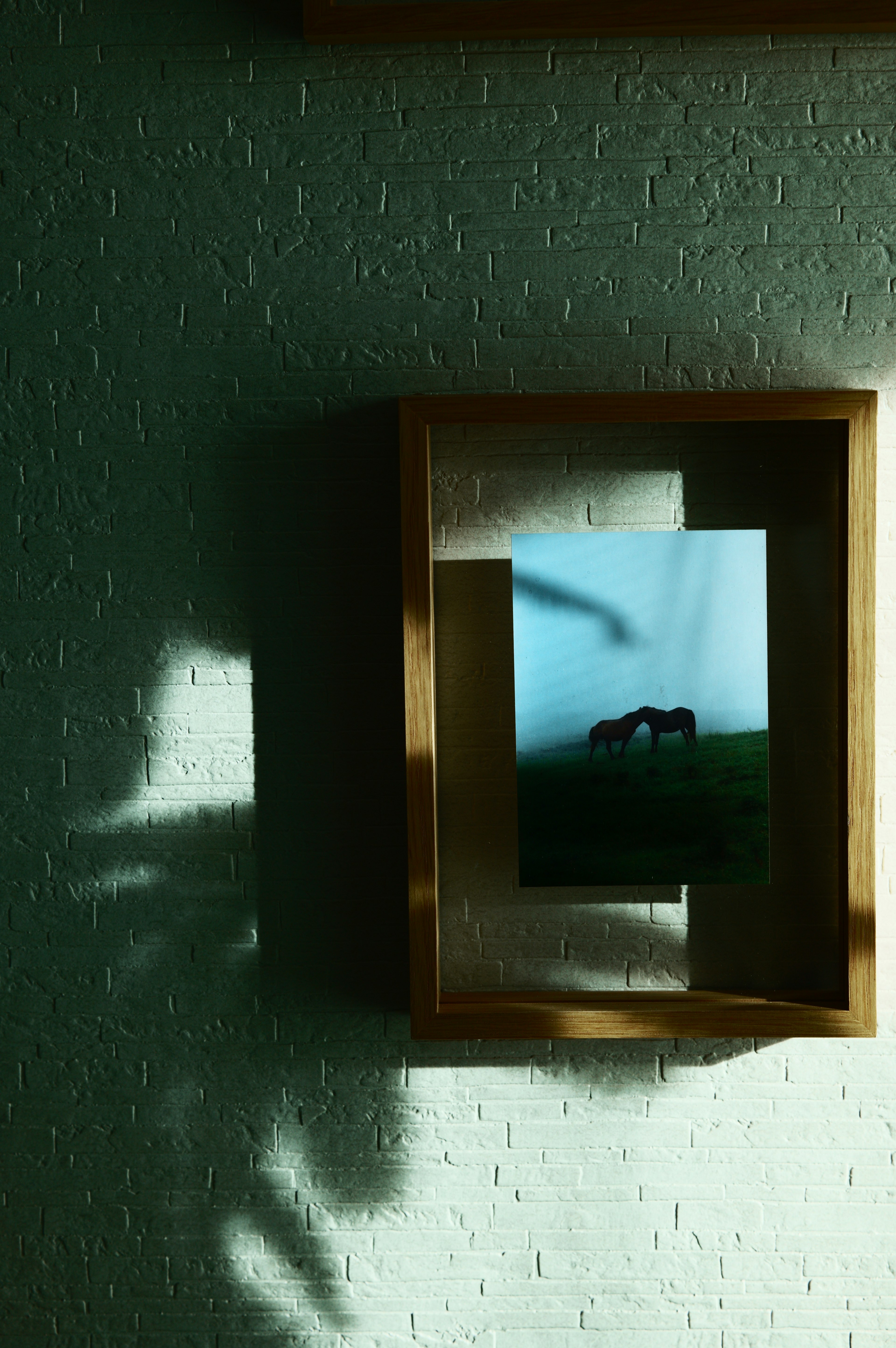 Una foto di paesaggio blu in una cornice di legno che proietta ombre sulla parete