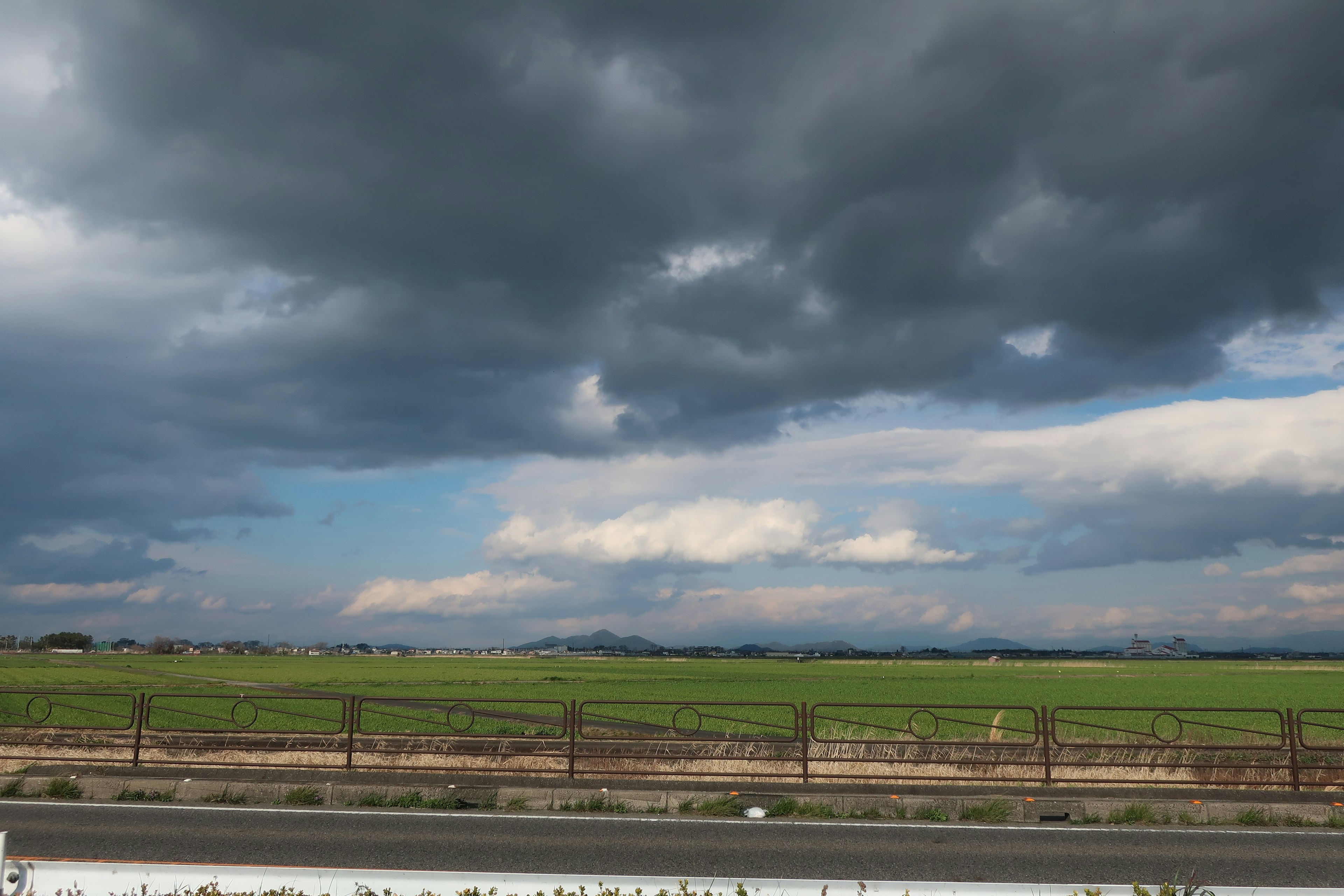 Paesaggio con campi verdi e nuvole scure