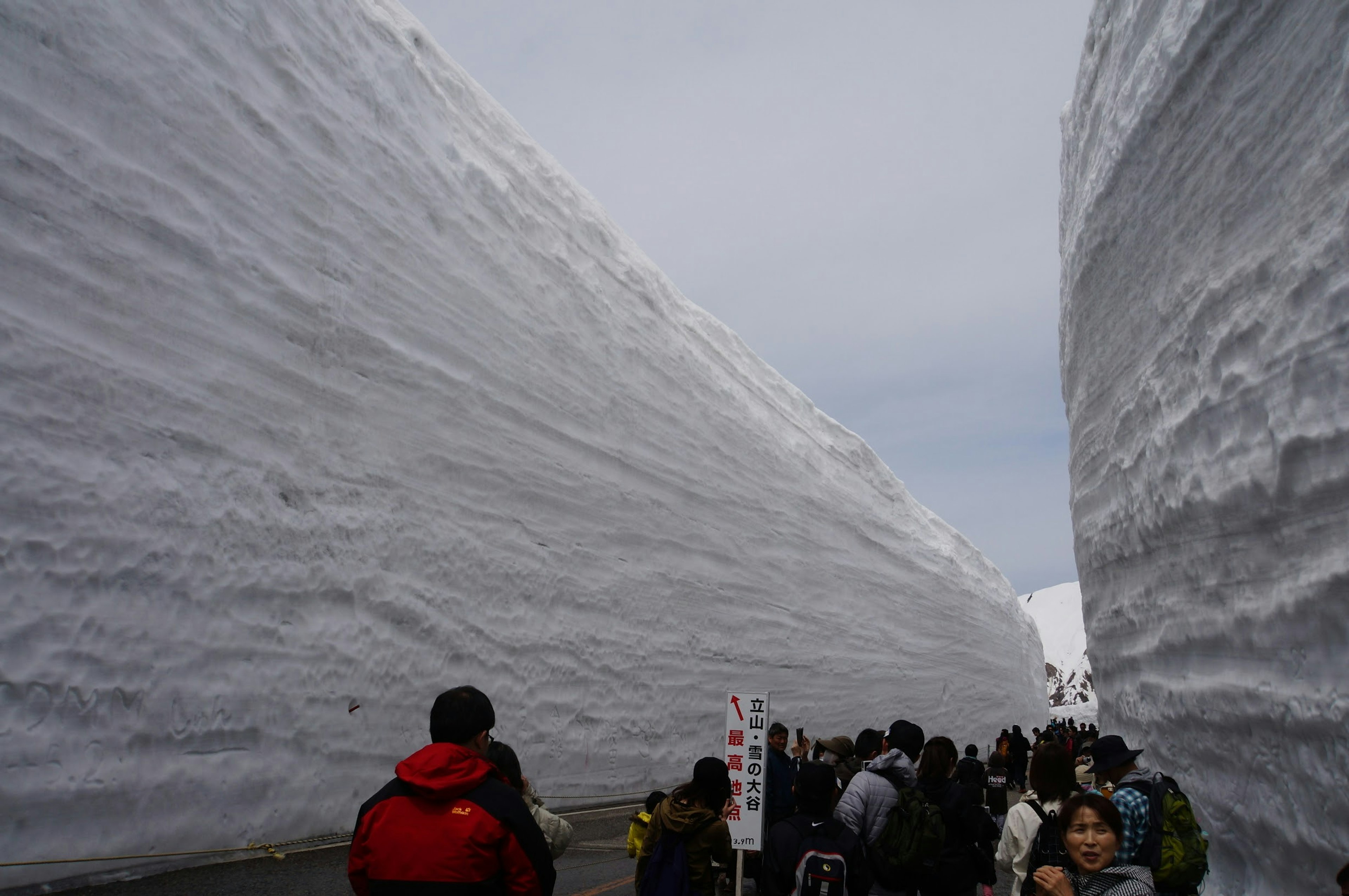 Tourists walking between towering snow walls