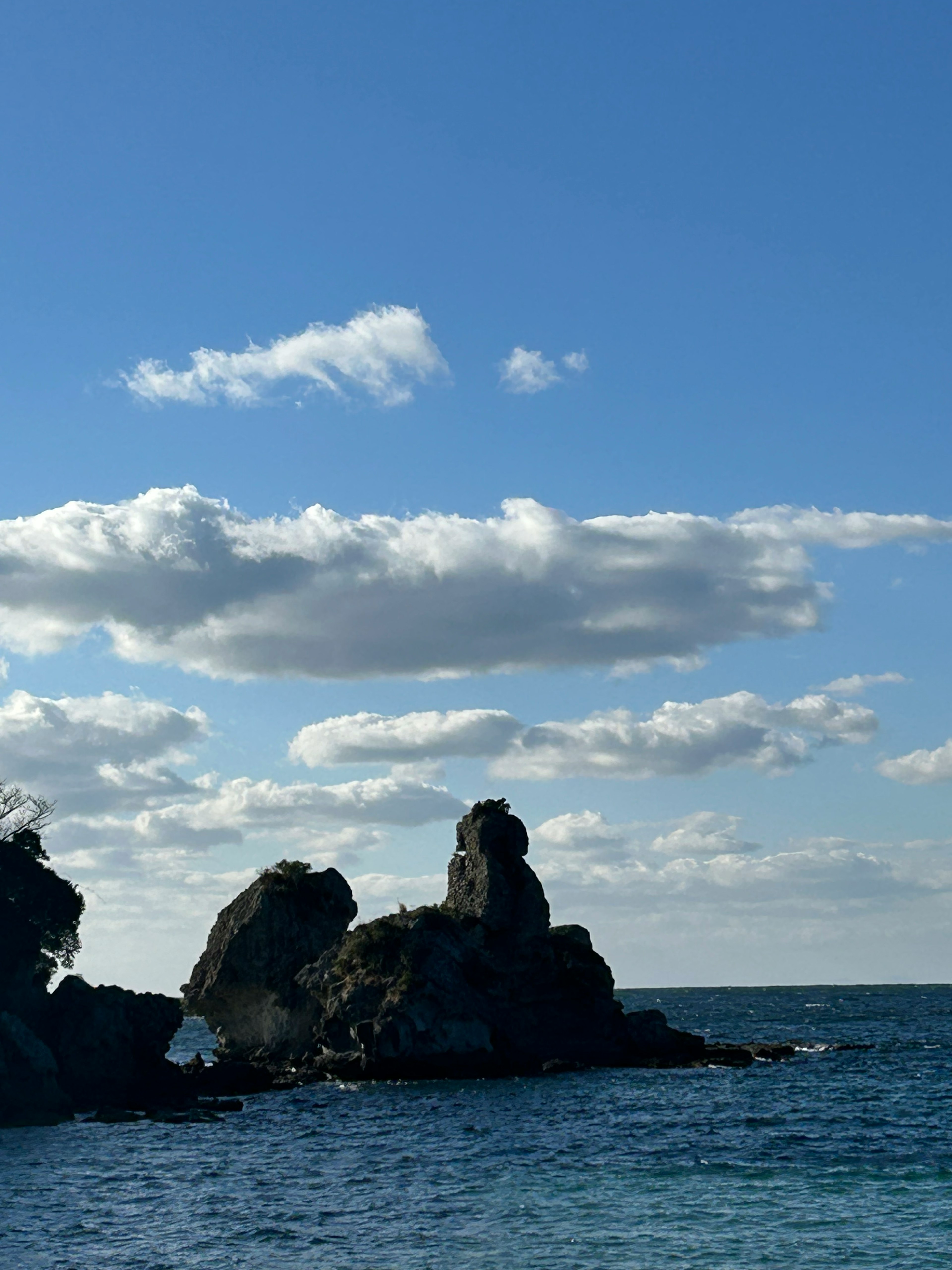 Rocks in the ocean under a blue sky with white clouds