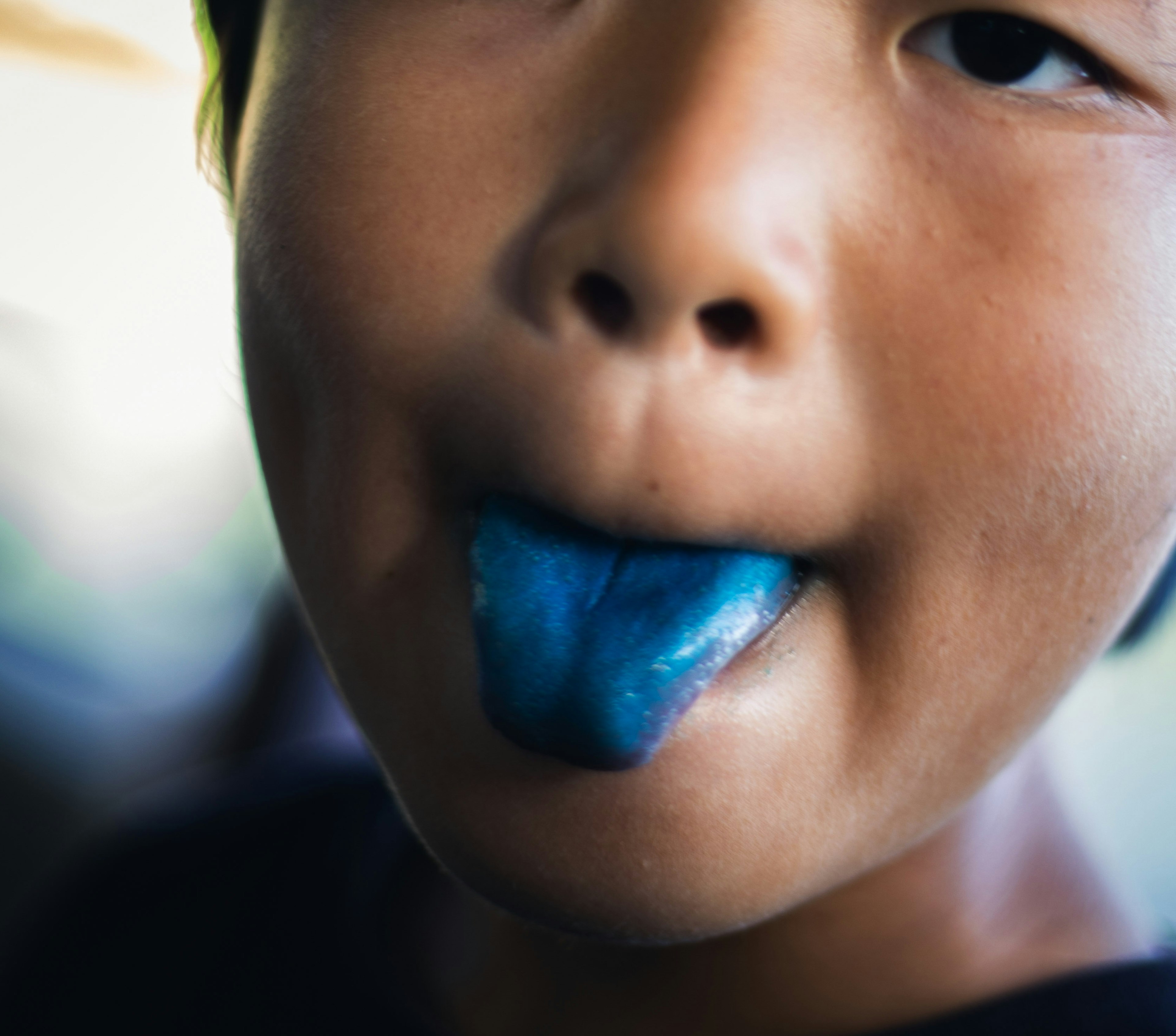 Close-up wajah anak yang menjulurkan lidah biru