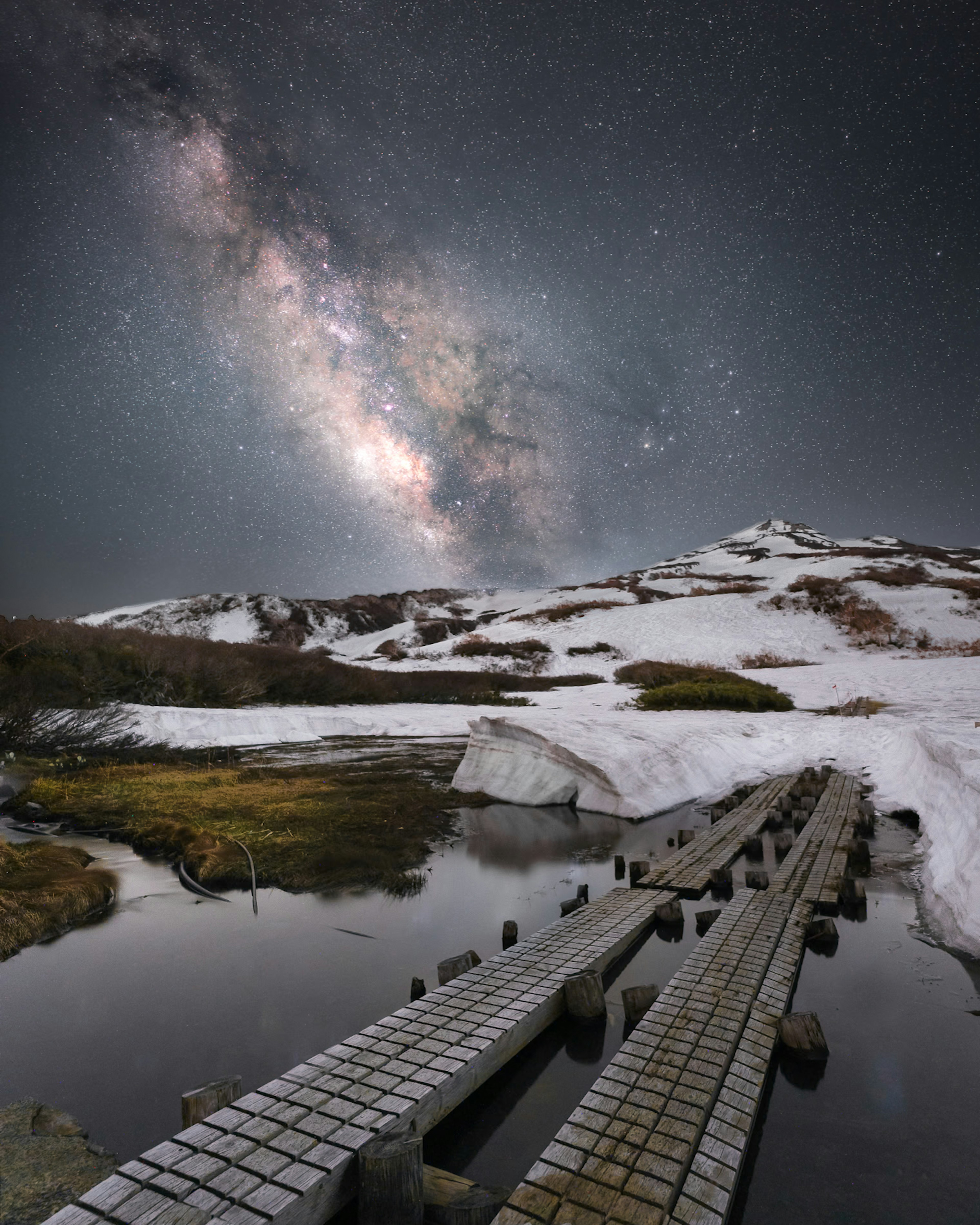 雪山上的星系與水中倒影的木橋