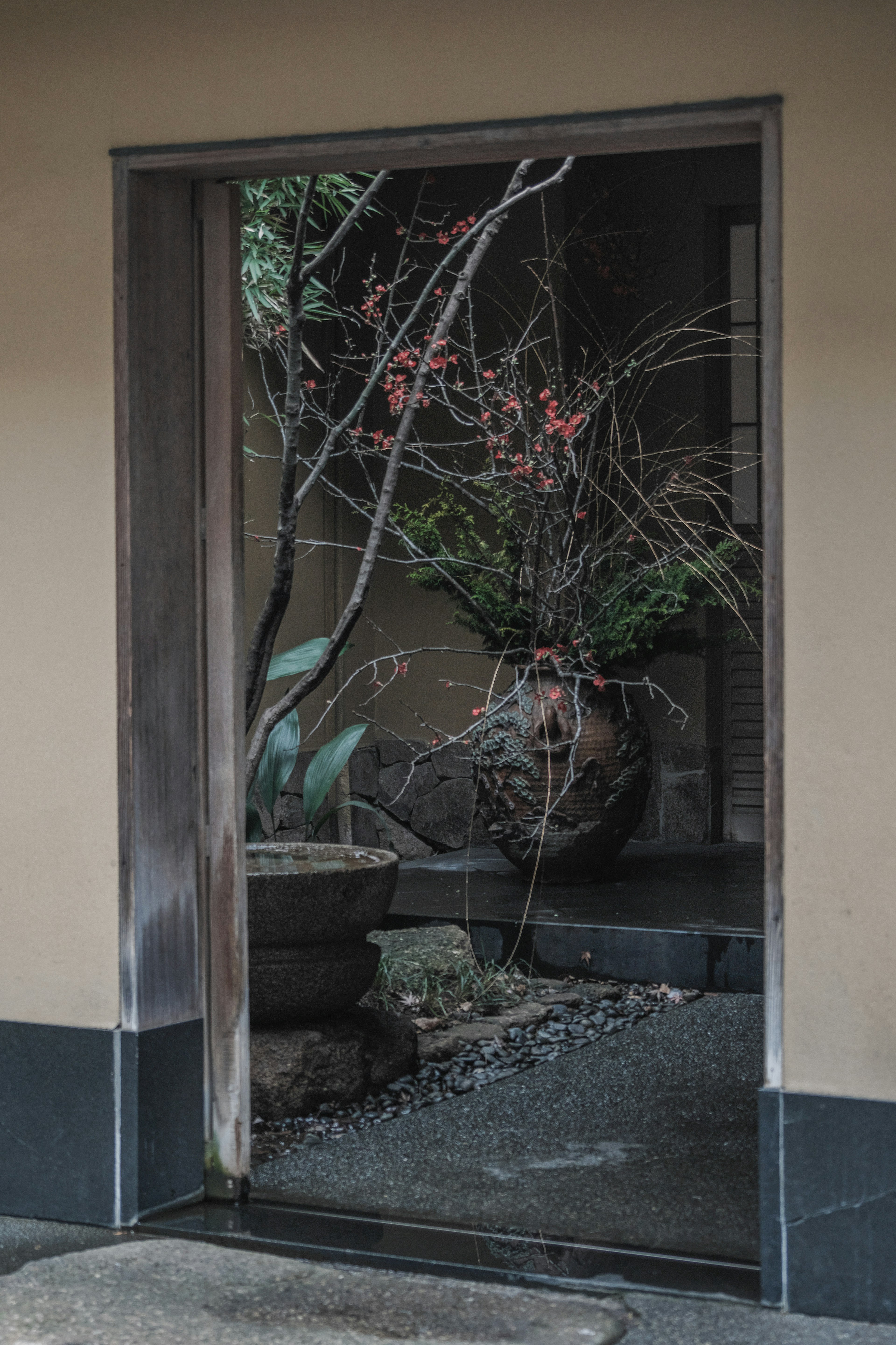 Porta in legno che si apre su un giardino giapponese sereno con fiori rossi