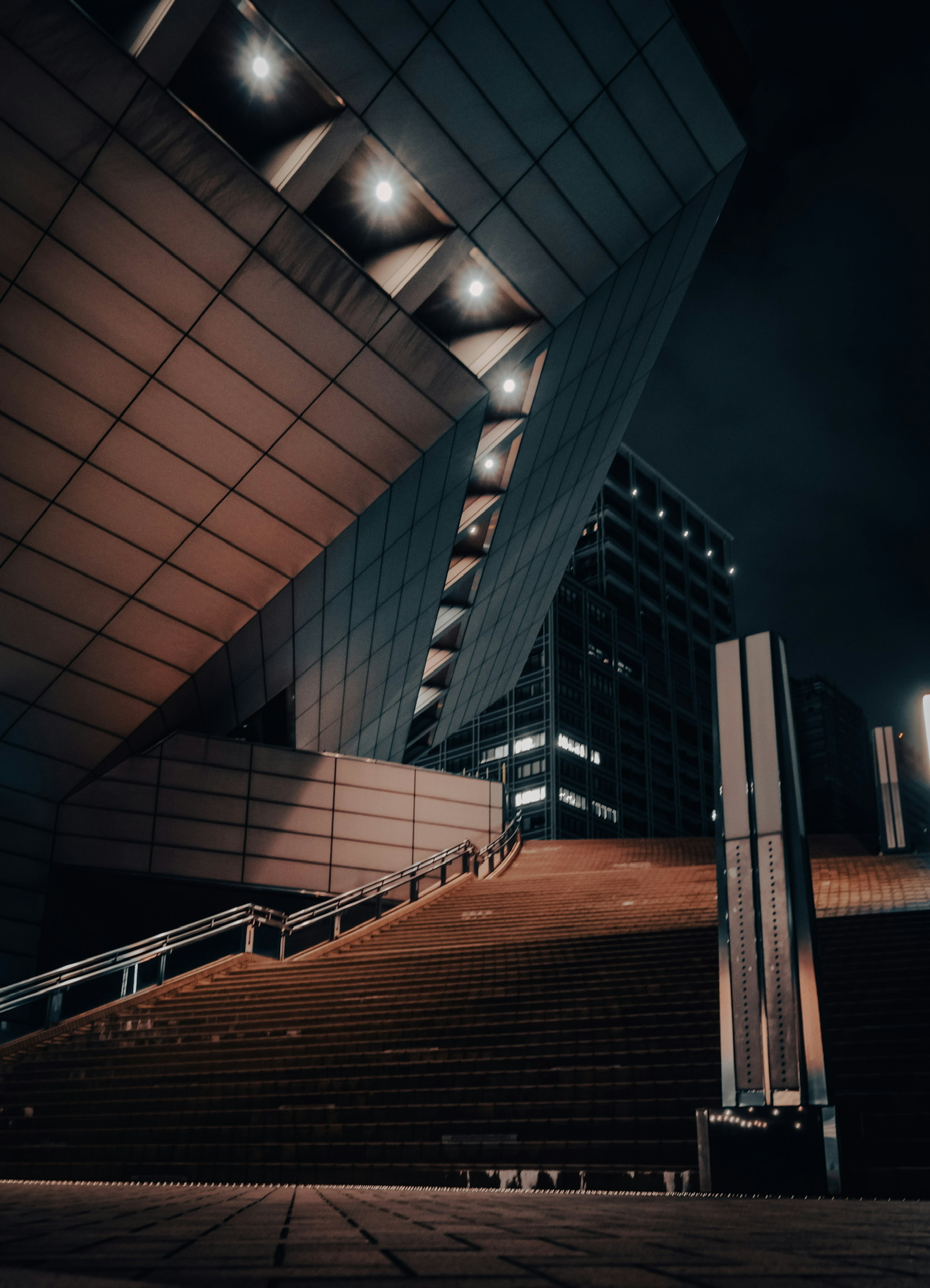 A modern building with striking angles in a nighttime urban setting