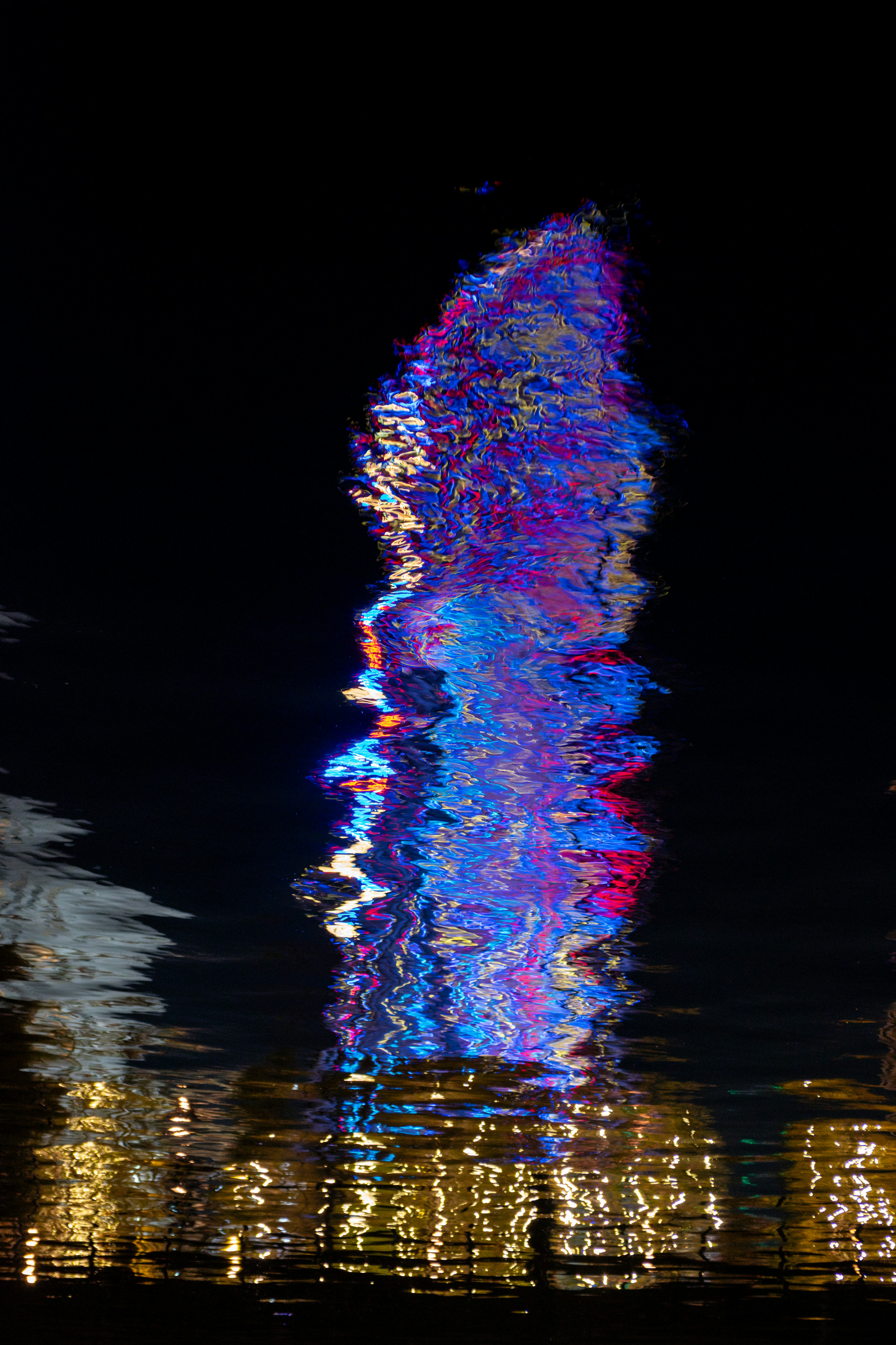 Colorful light patterns reflected on water in a nighttime scene