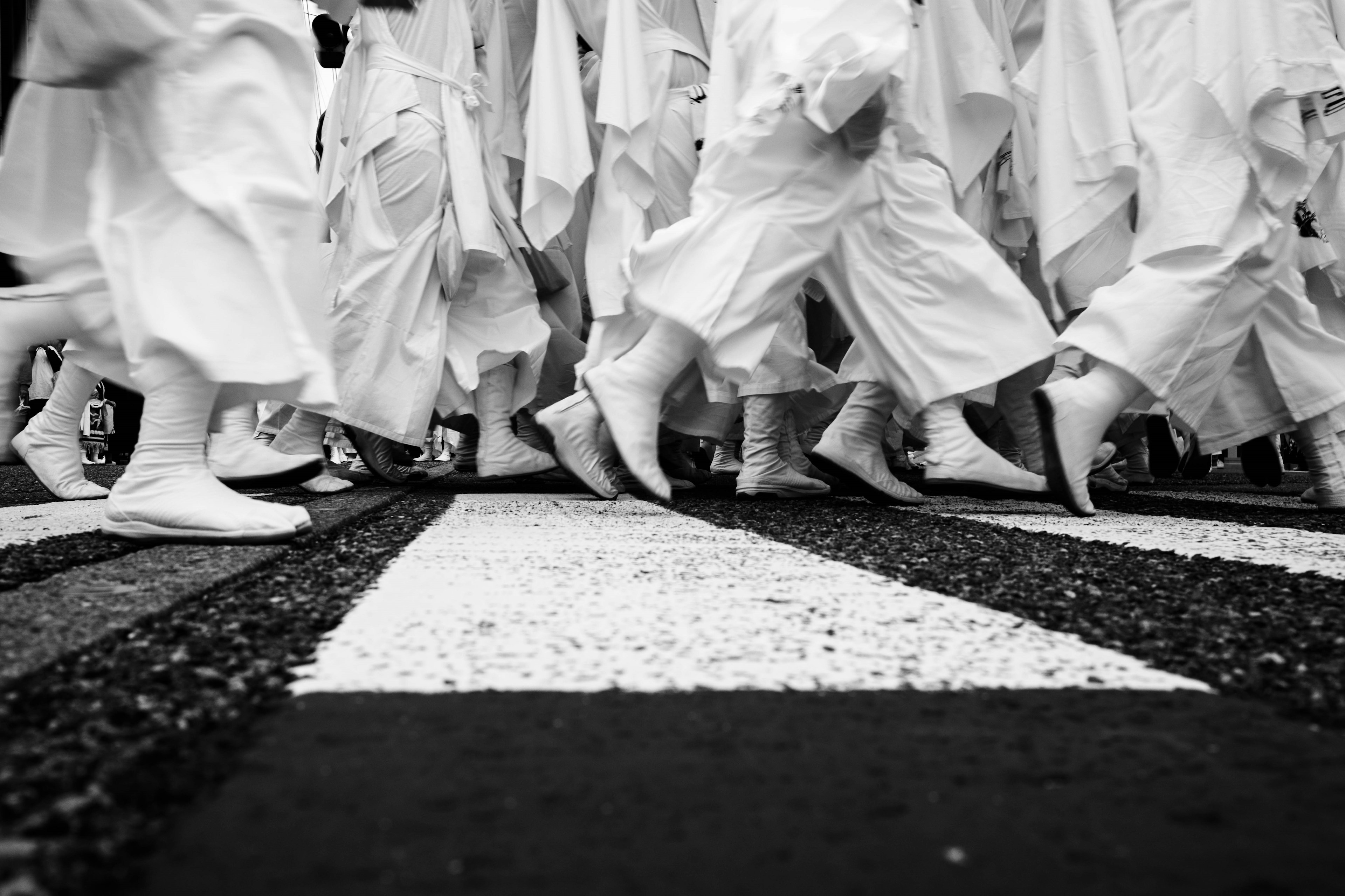 People in white garments walking across a crosswalk