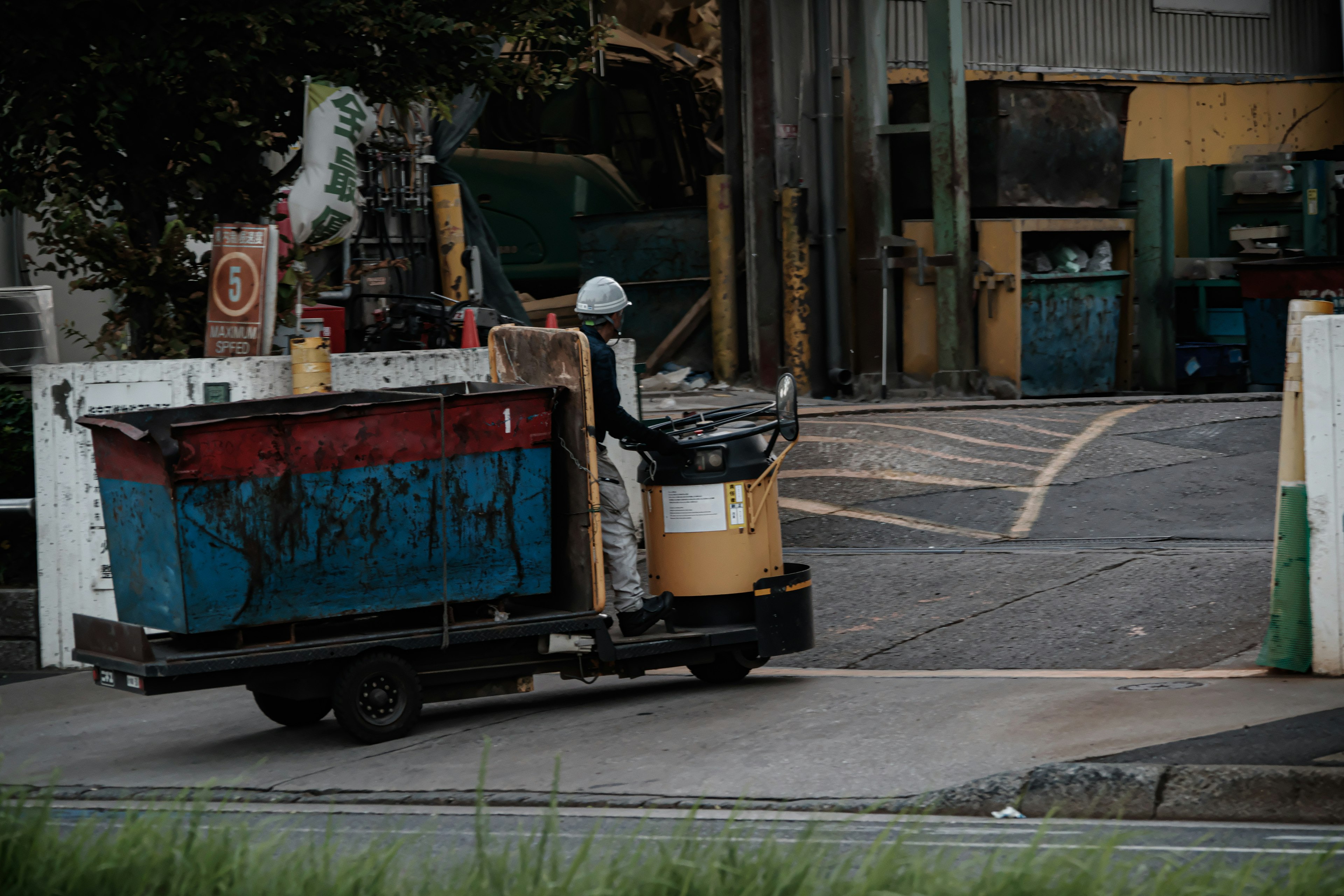 Un travailleur conduisant un véhicule de collecte des déchets coloré à l'extérieur d'une usine