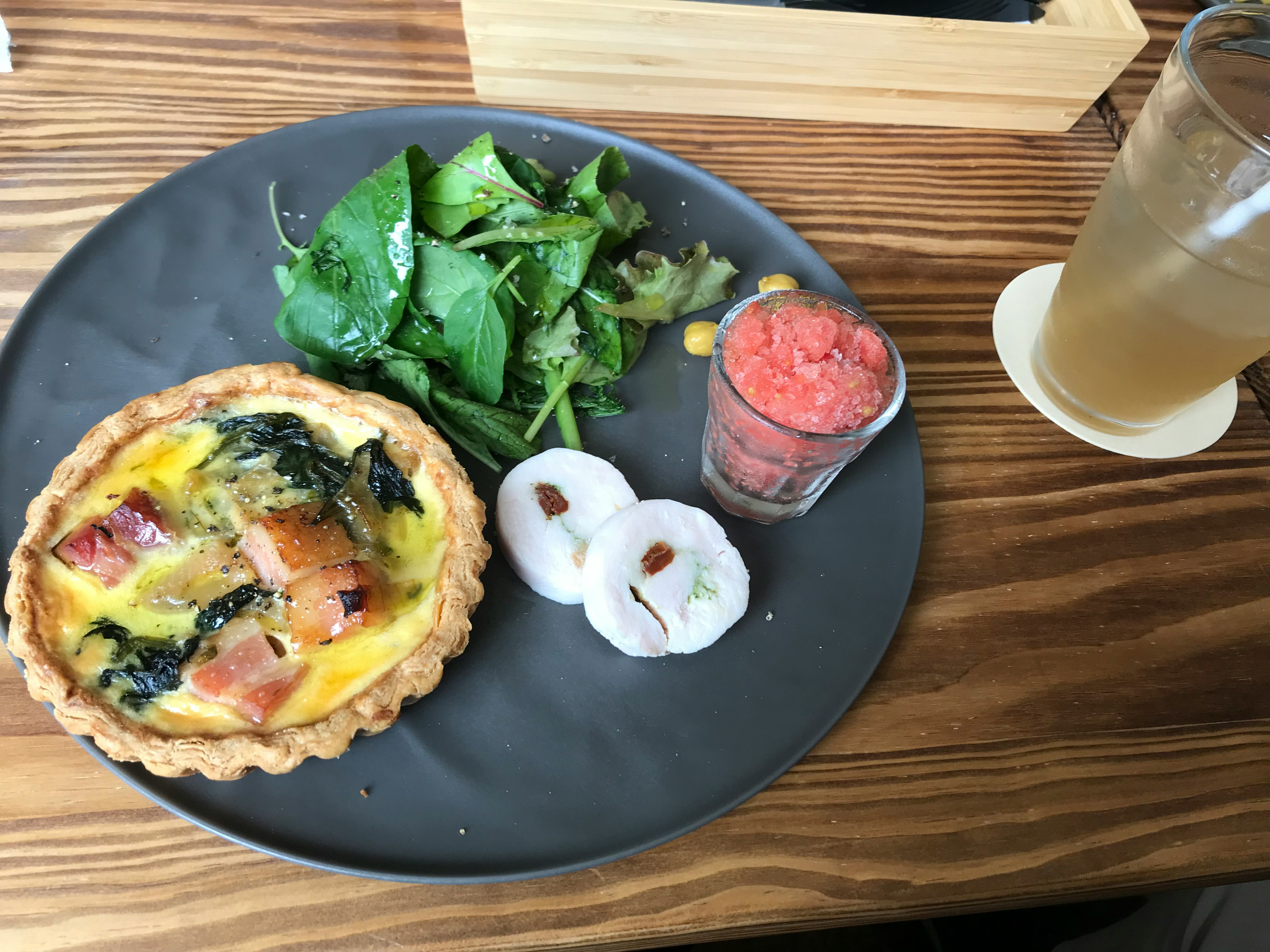 Bánh quiche rau chân vịt và giăm bông với salad, món tráng miệng trái cây và đồ uống trên đĩa