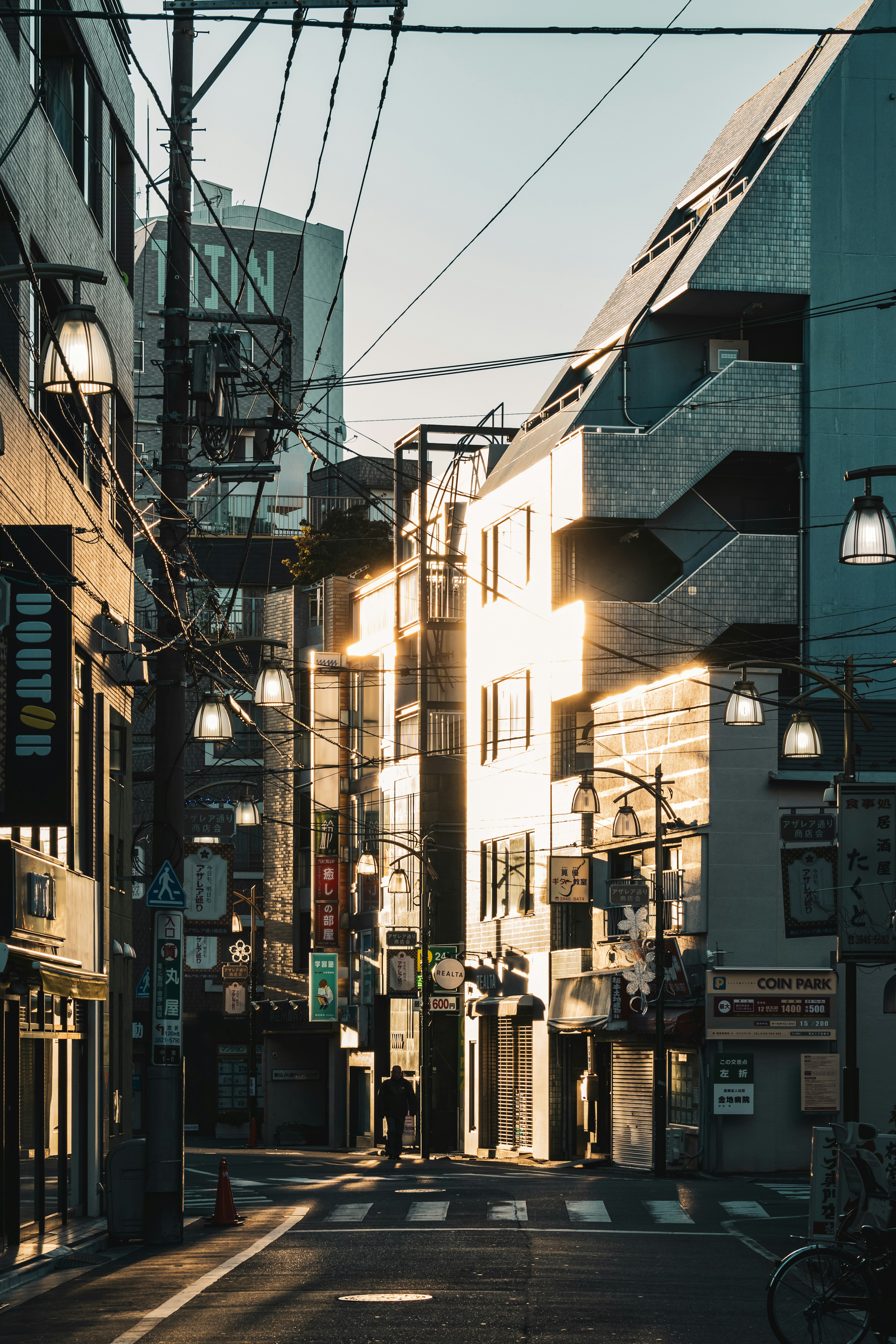 街の通りに面した建物が夕日を反射し、街灯が灯る風景