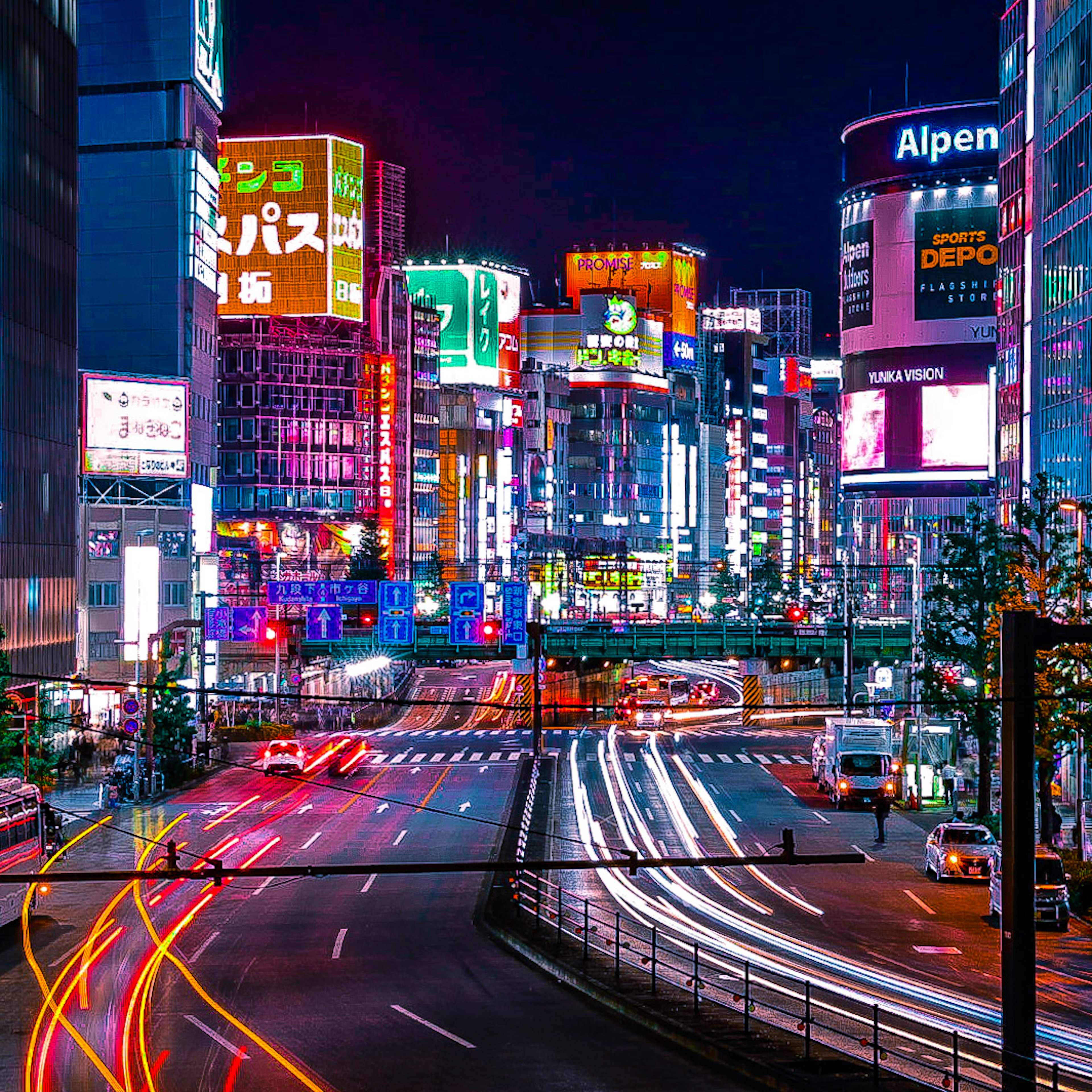 夜の東京の繁華街にある明るいネオンと車のライト