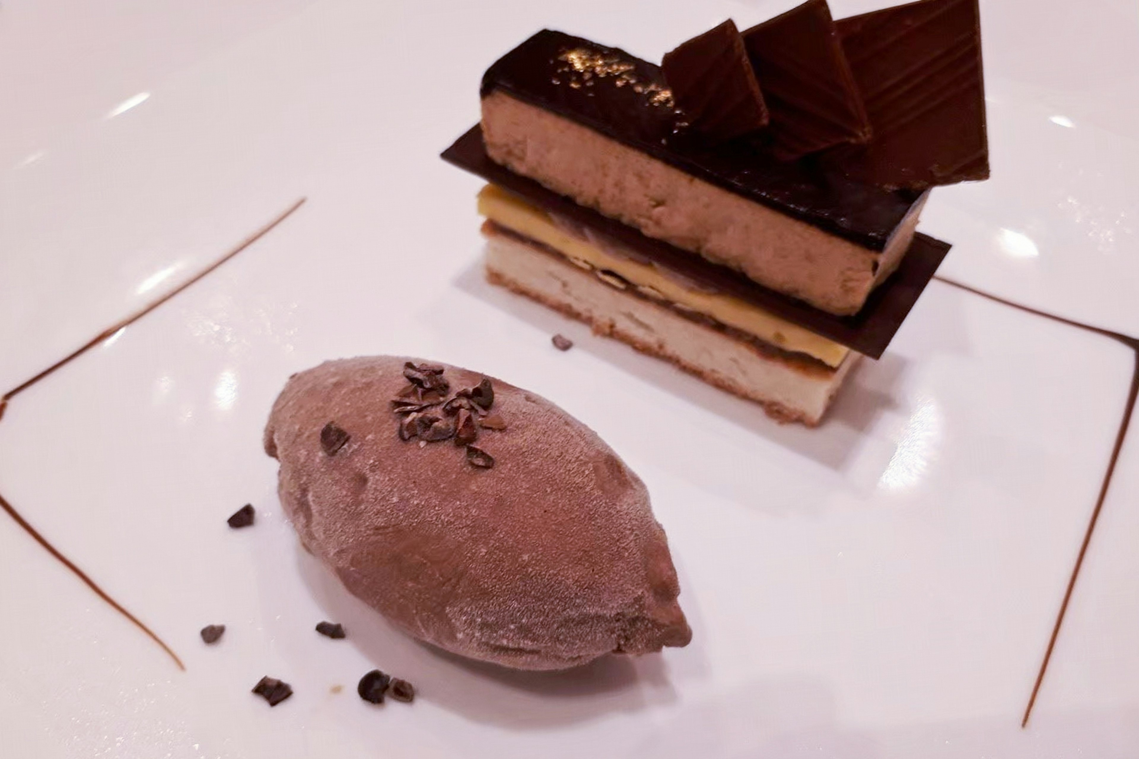 Presentazione elegante di dessert con strati di cioccolato e una pallina di sorbetto al cioccolato