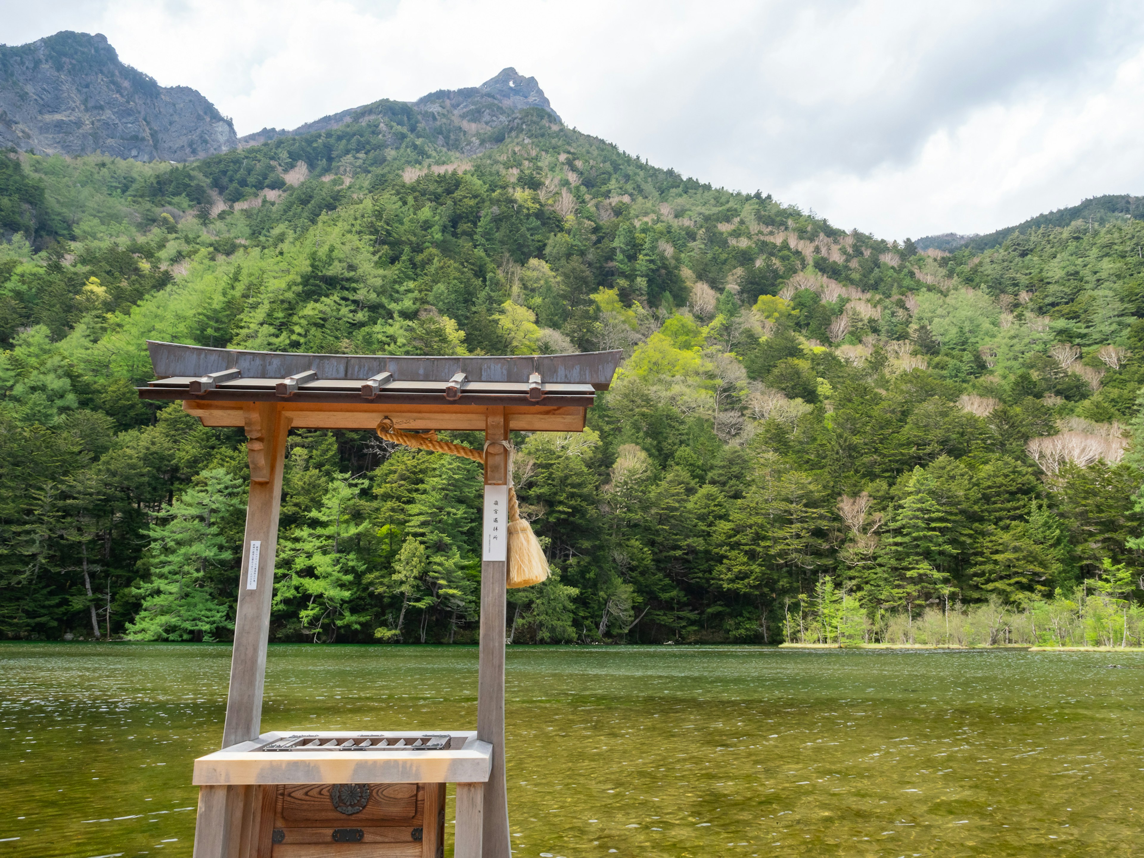 美しい山の風景と静かな湖の近くの木製のベンチ