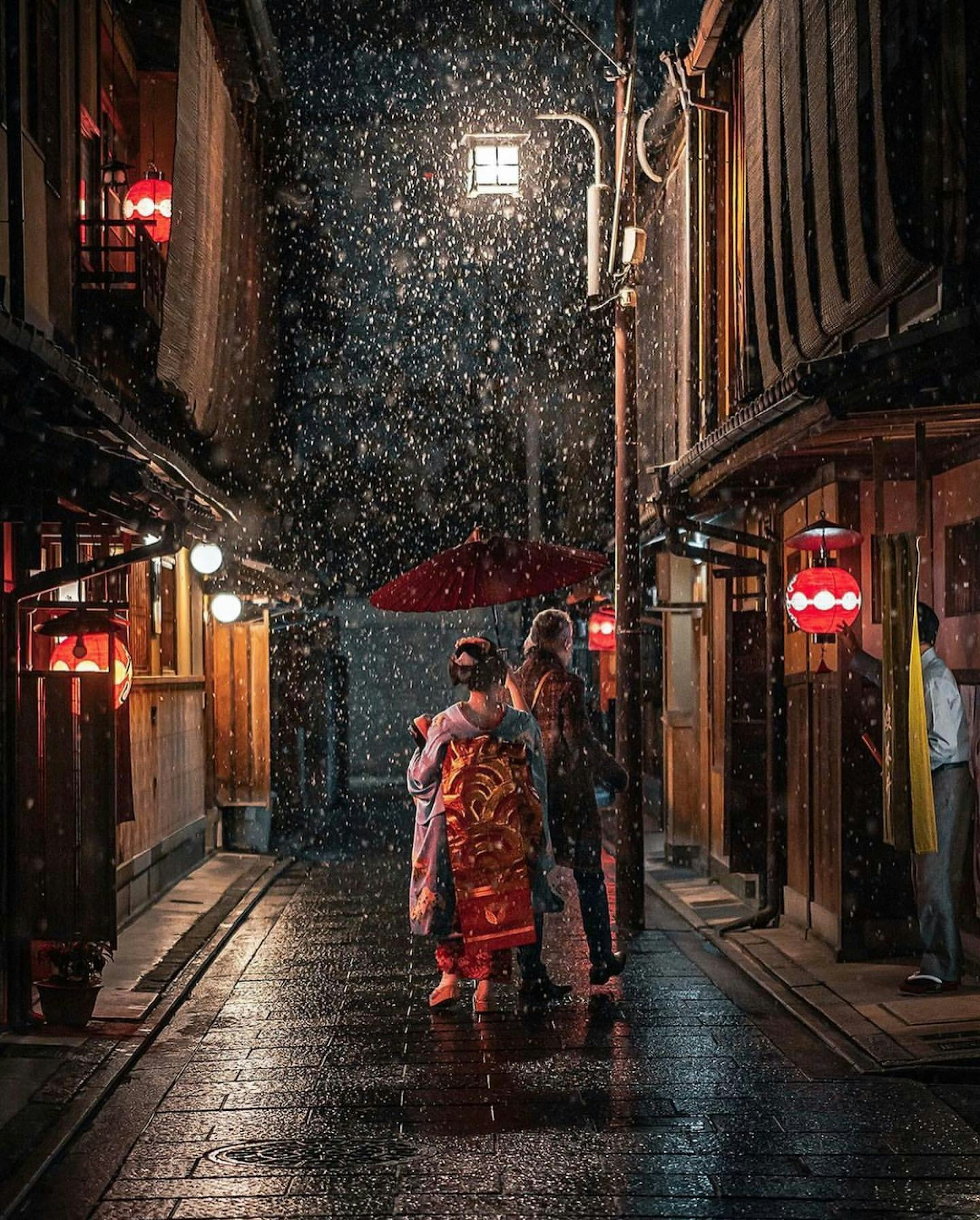 Una mujer en kimono y un hombre con un paraguas caminando bajo la lluvia