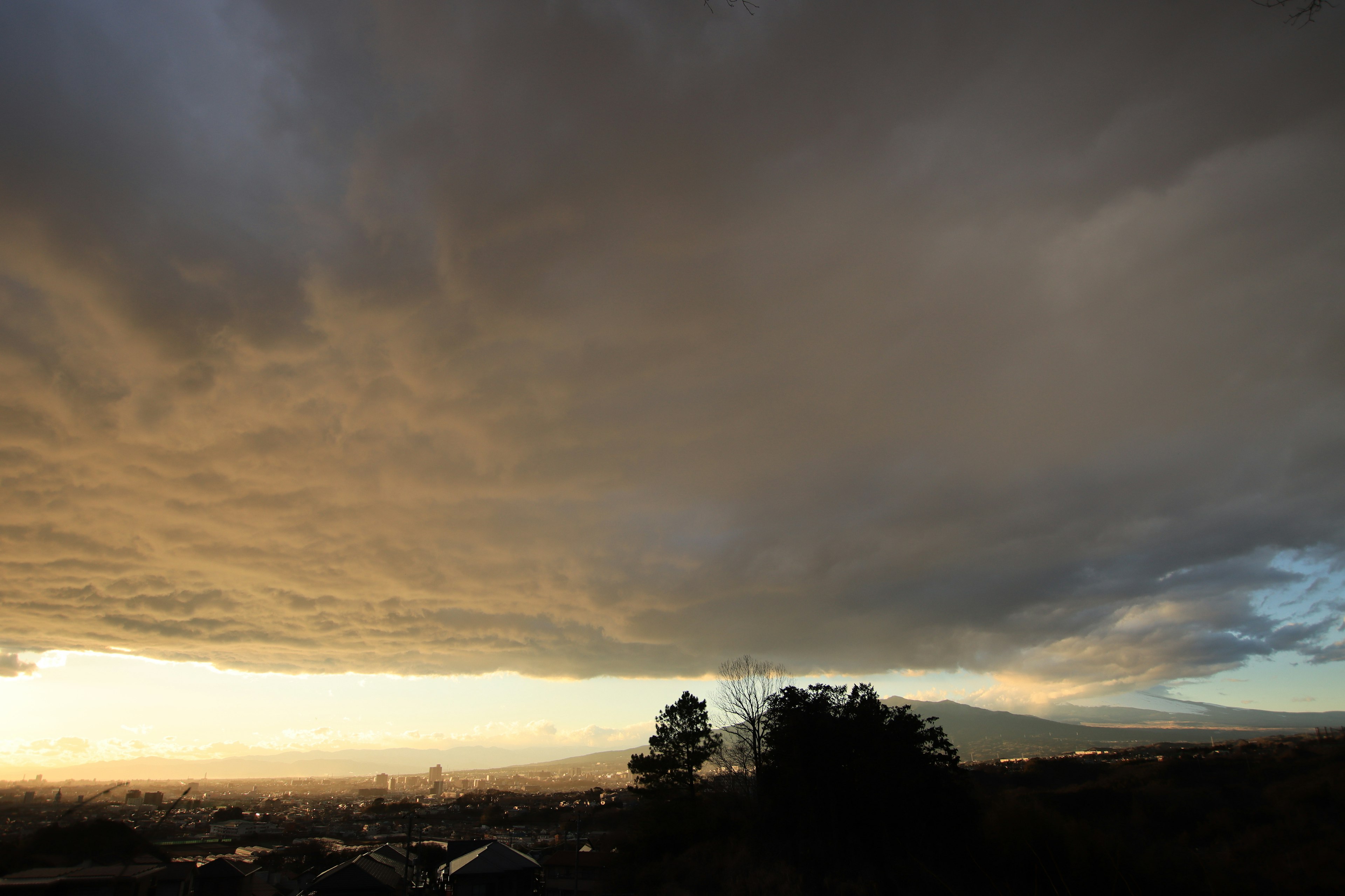 Dramatische Wolken über einer Sonnenuntergangslandschaft mit Bergen