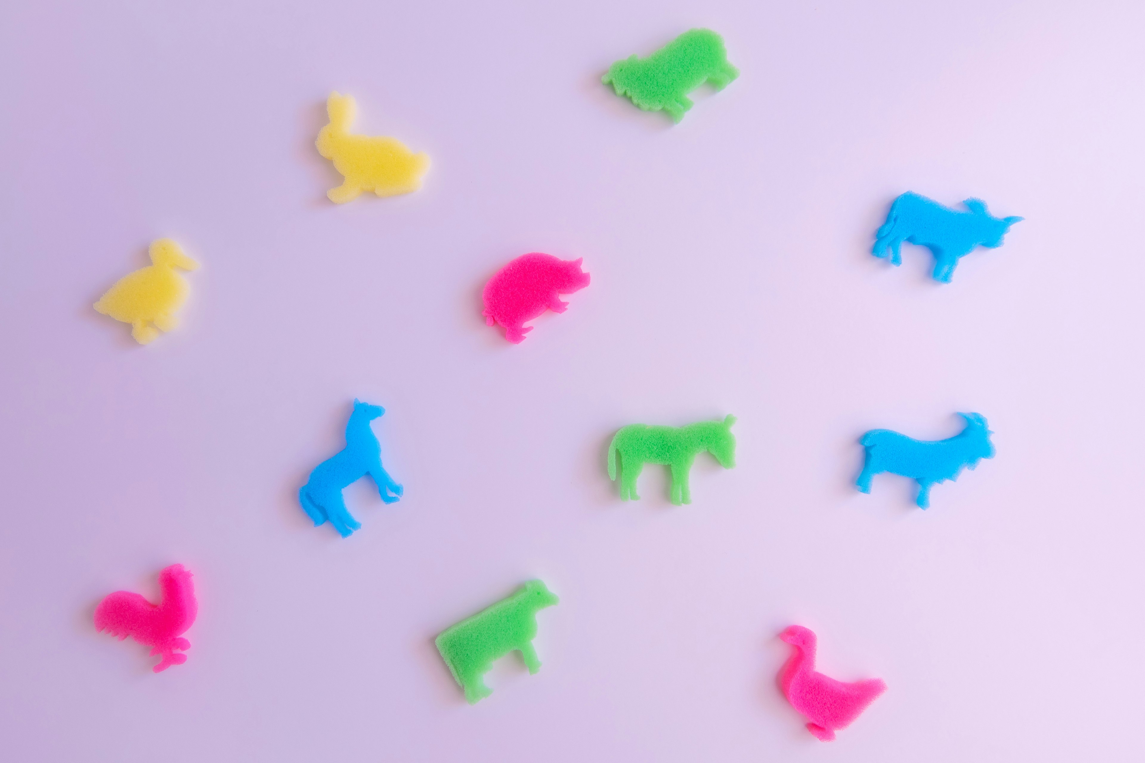 Colorful plastic animal figures scattered on a pink background