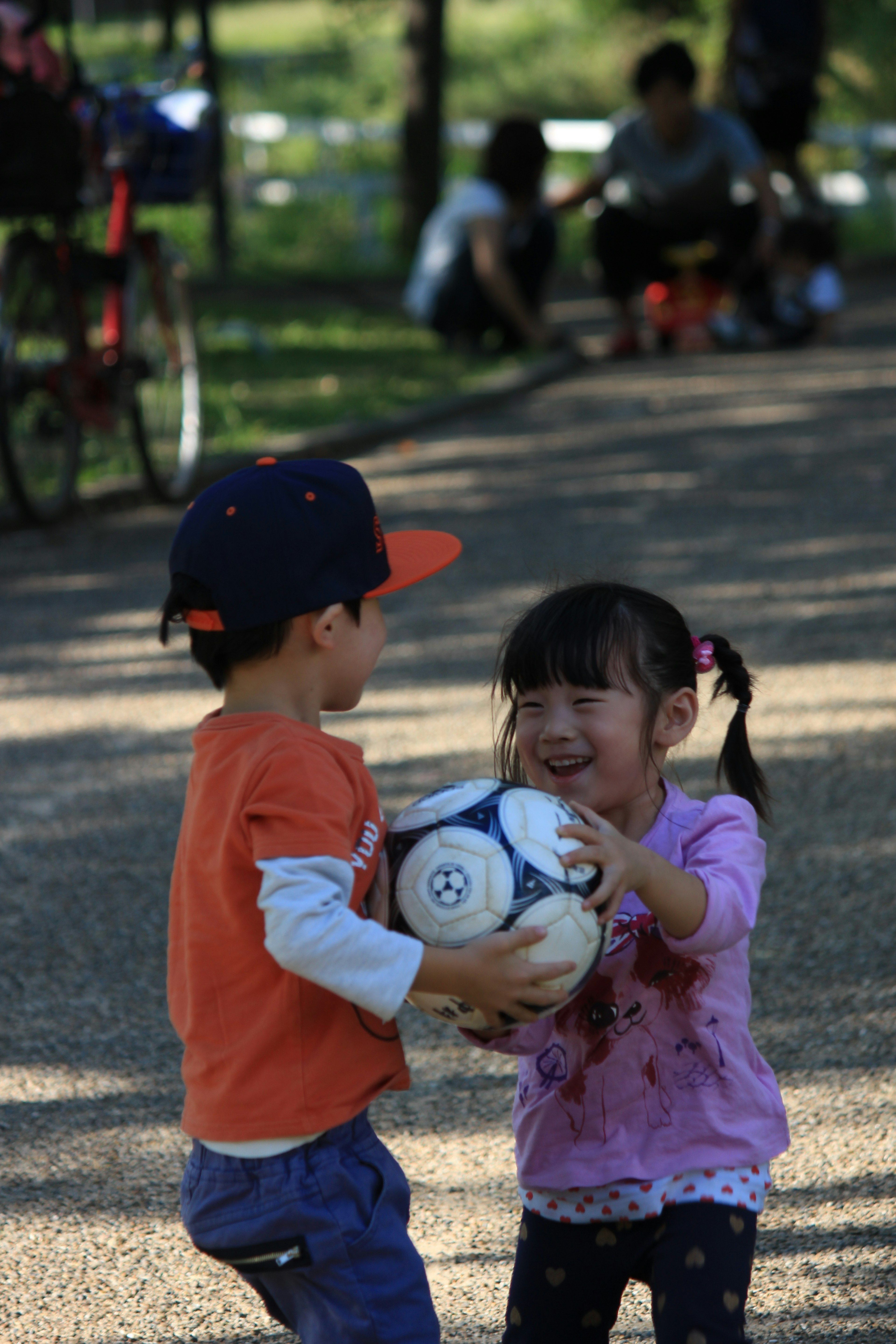 Zwei Kinder spielen mit einem Fußball in einem Park