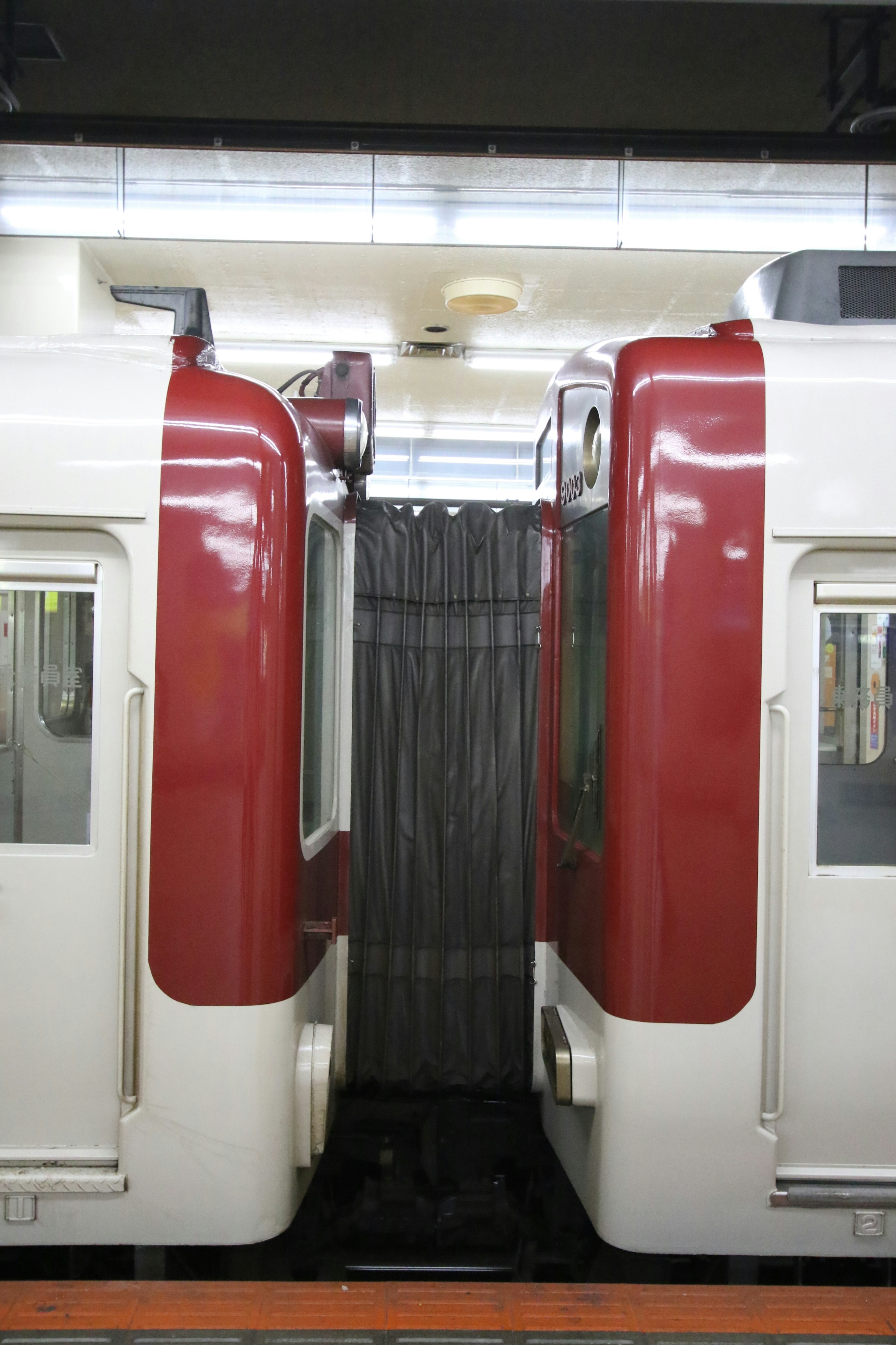 Two red and white train cars at a station