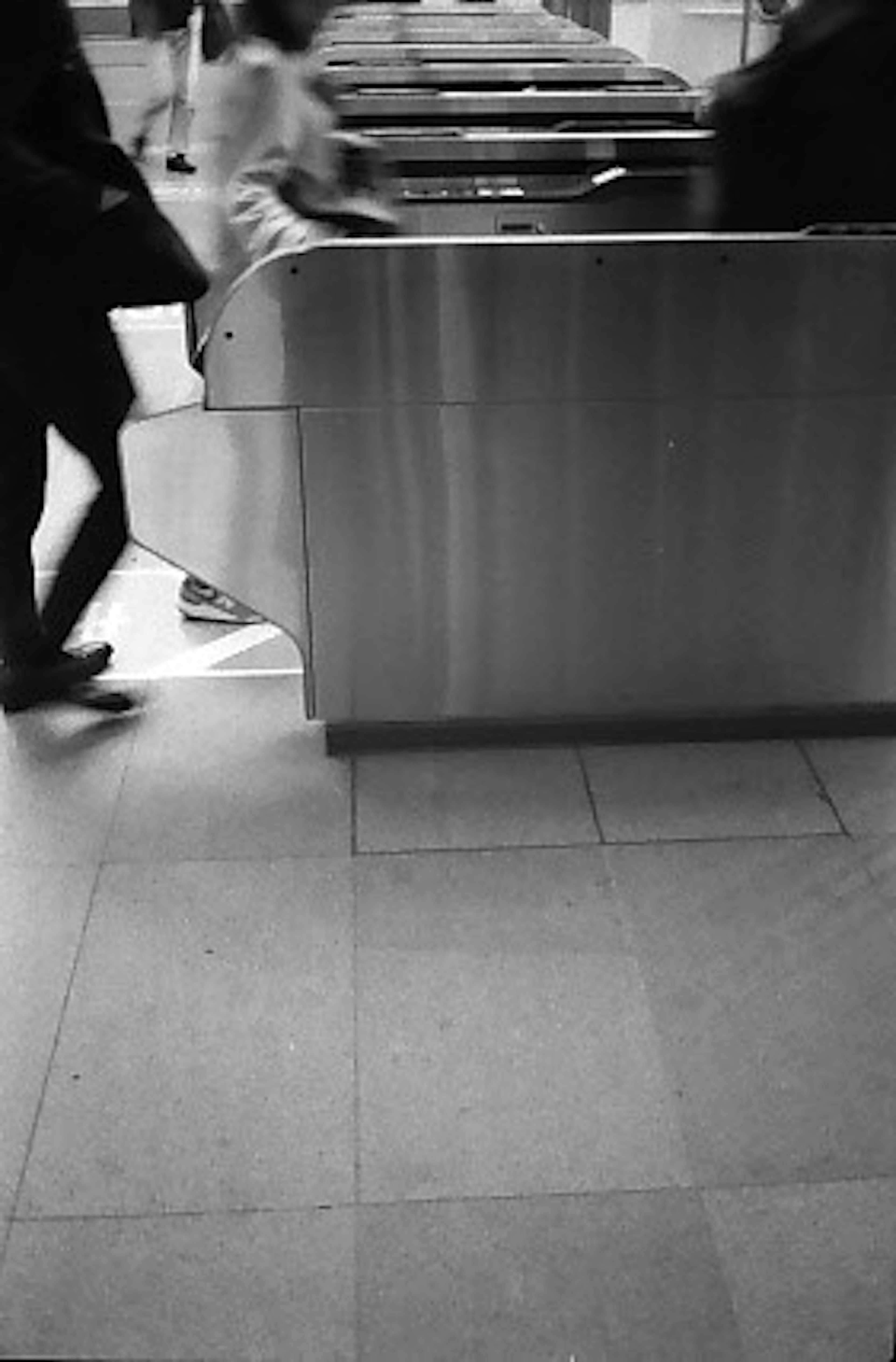 Metal turnstile with people passing through and tiled floor