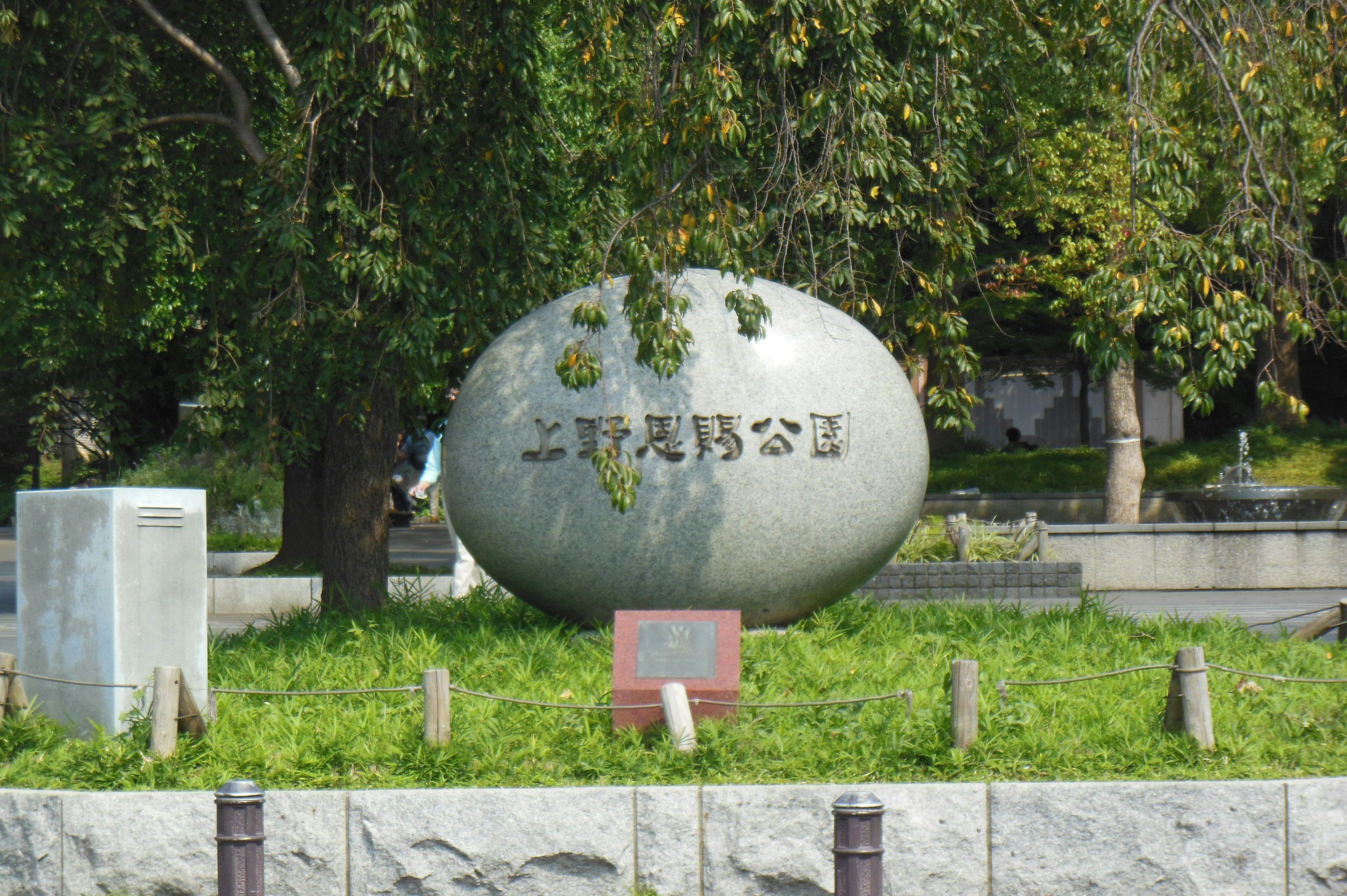 Großer eiförmiger Stein mit eingravierten Buchstaben in einem Park