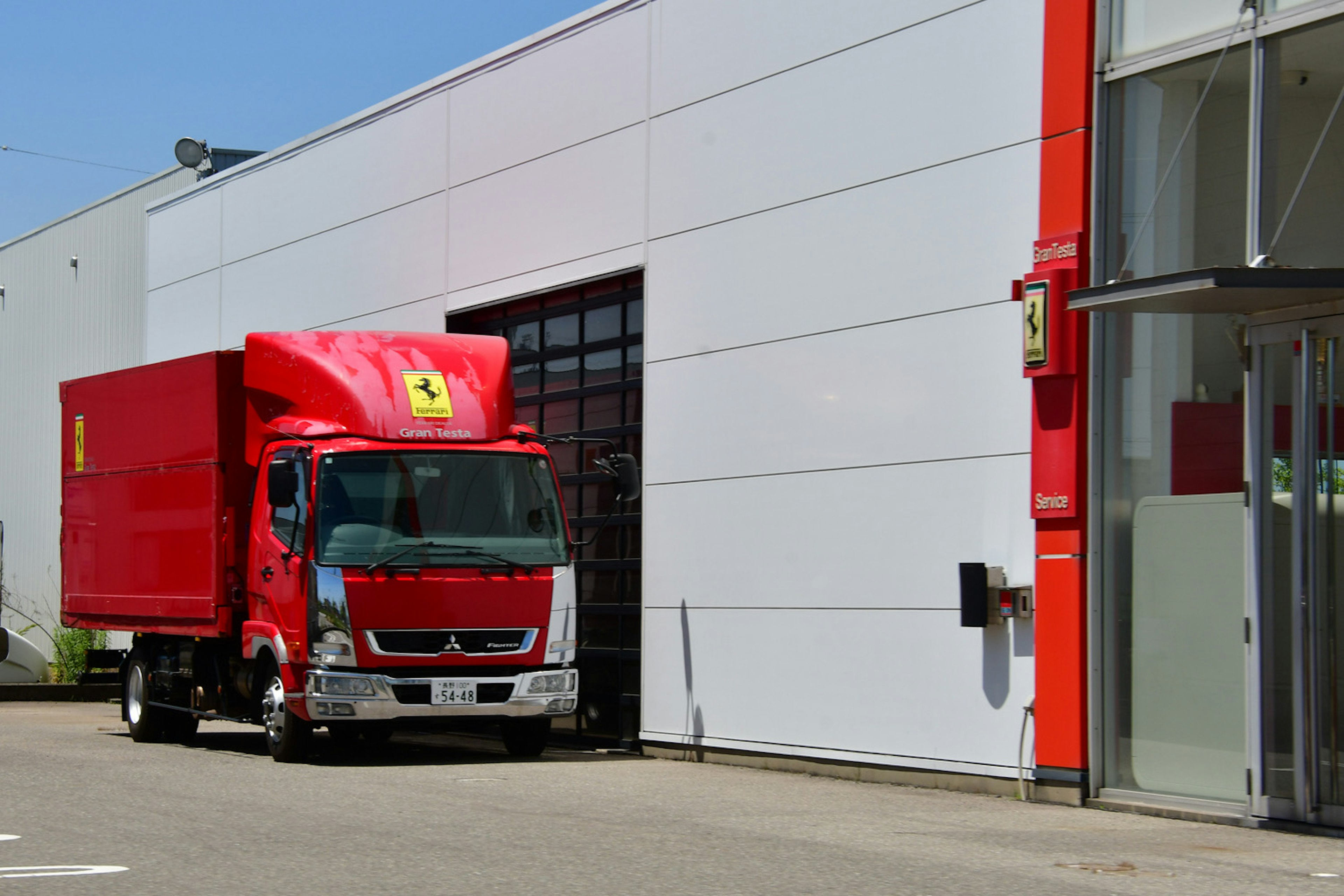 Camion Ferrari rosso parcheggiato davanti a un edificio bianco